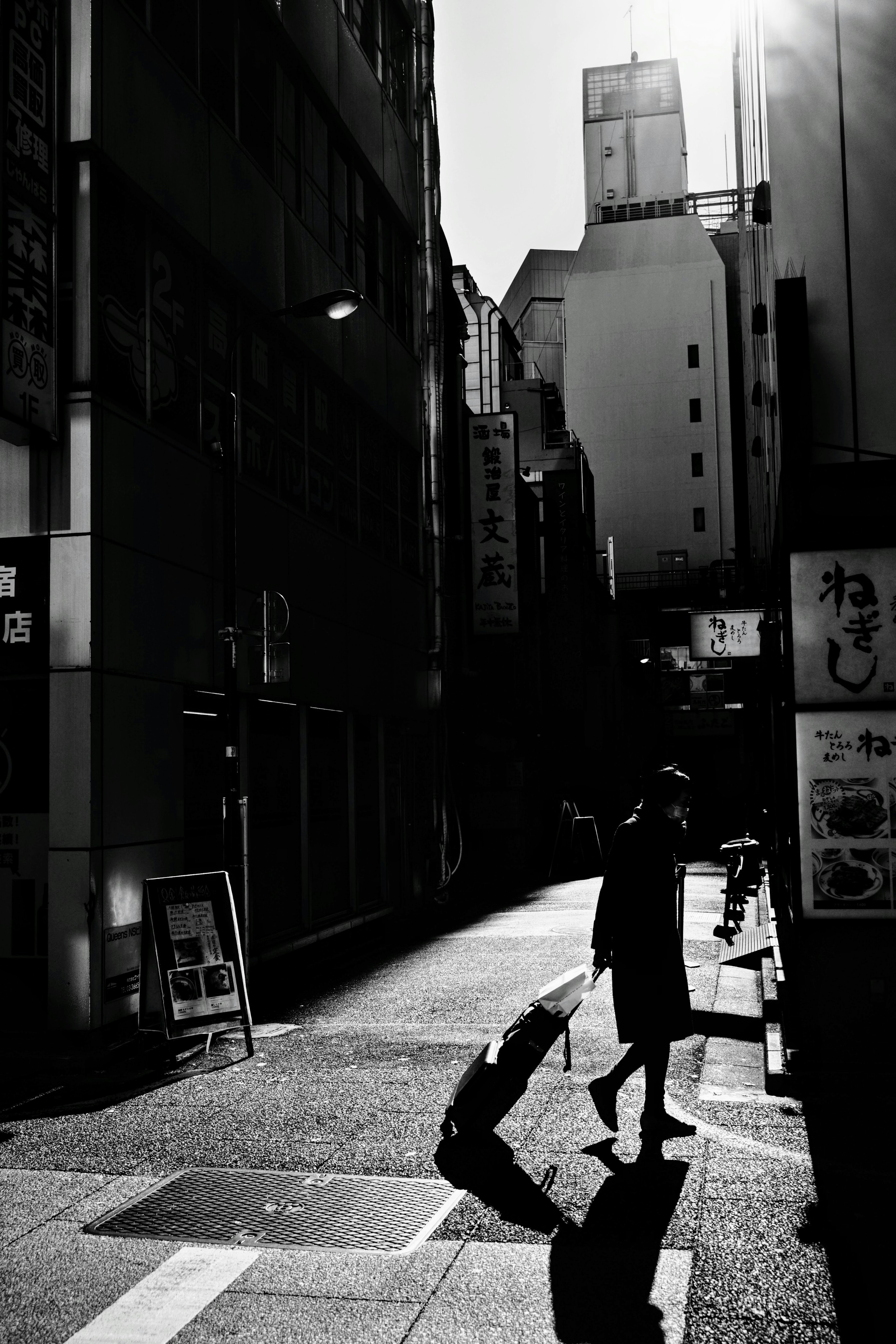 Silhouette of a person walking in a narrow alley with strong contrast in black and white