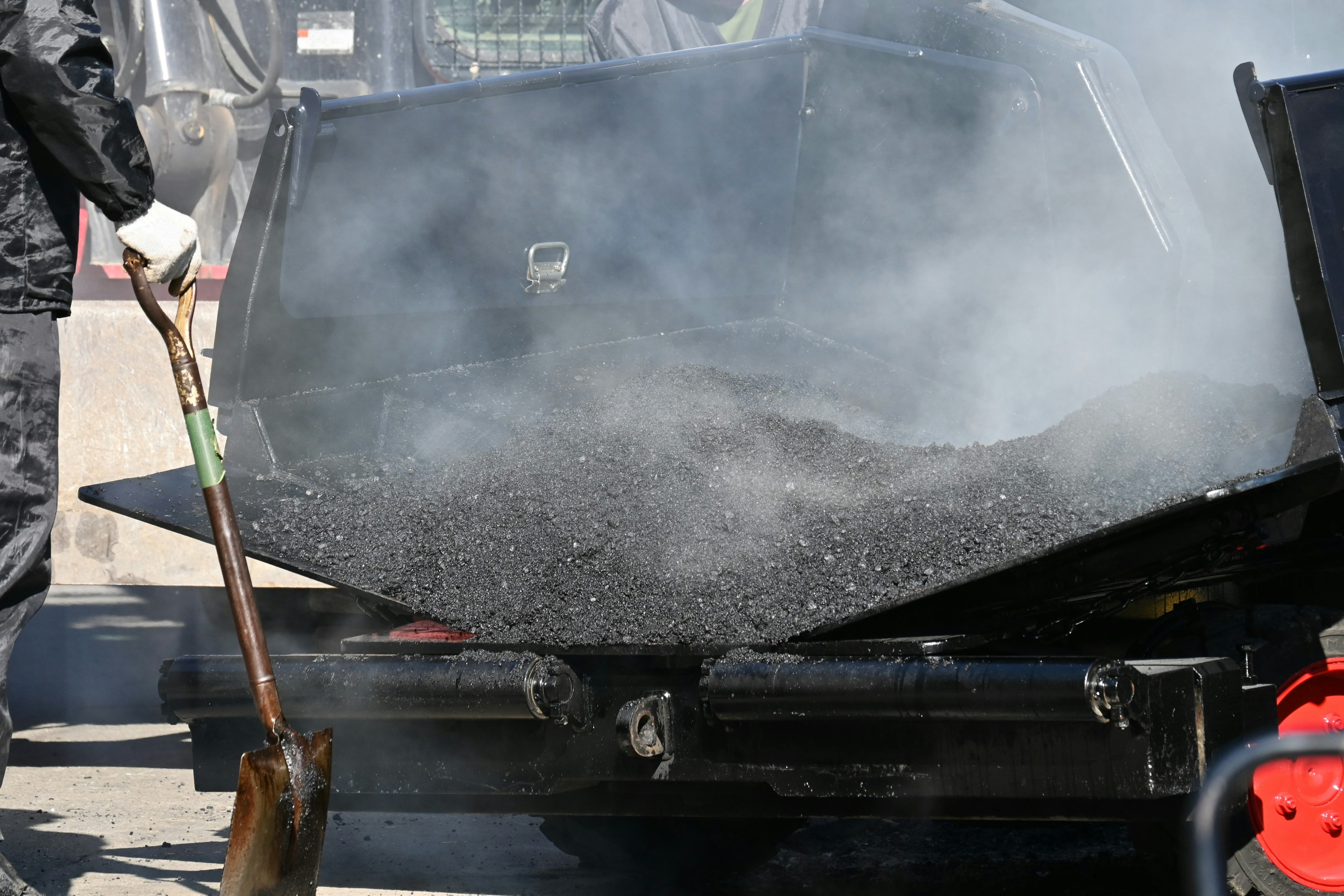 Un camión descargando asfalto con humo que se eleva