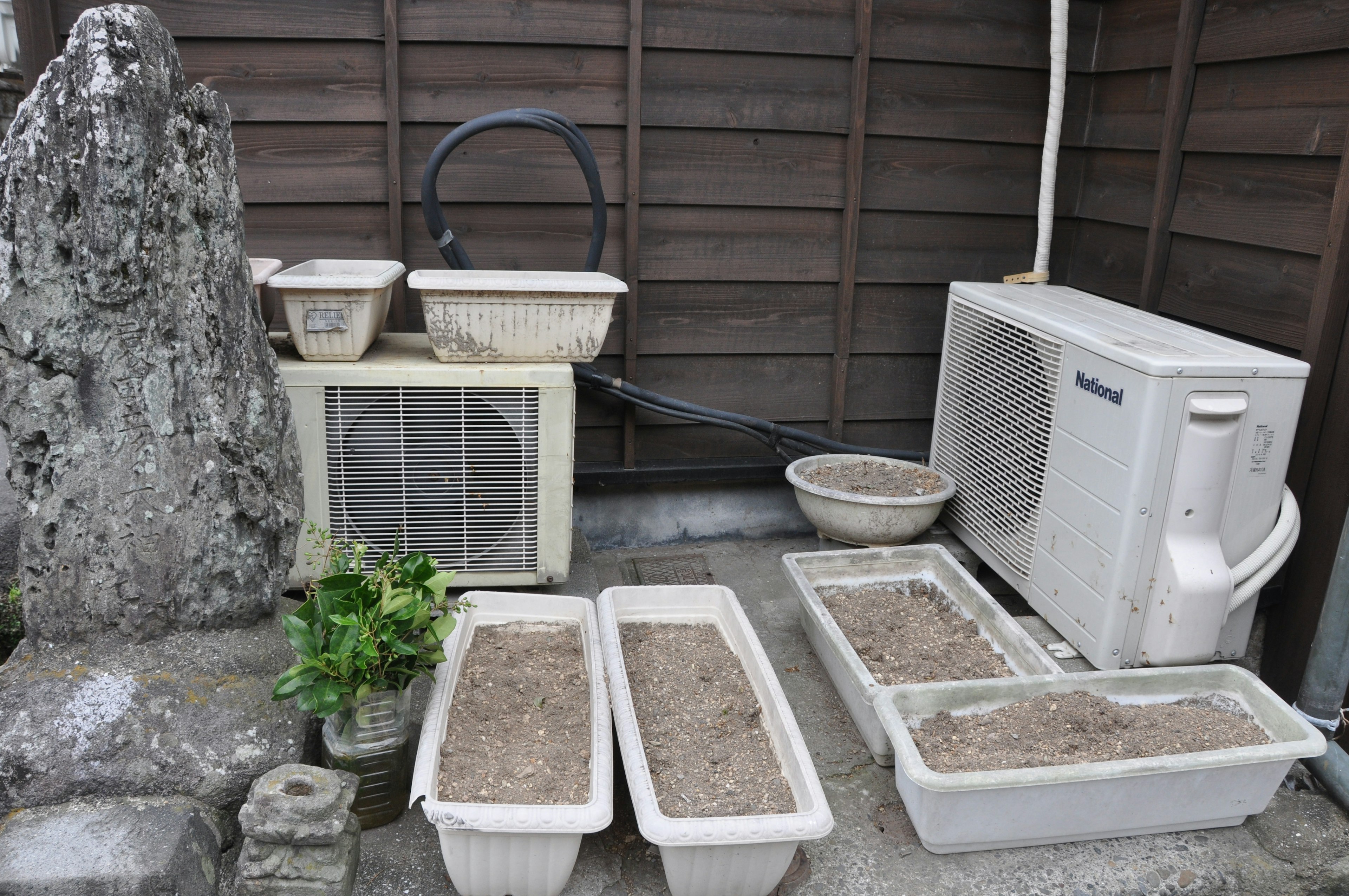 Bacs à fleurs et unité extérieure de climatisation dans un coin de jardin