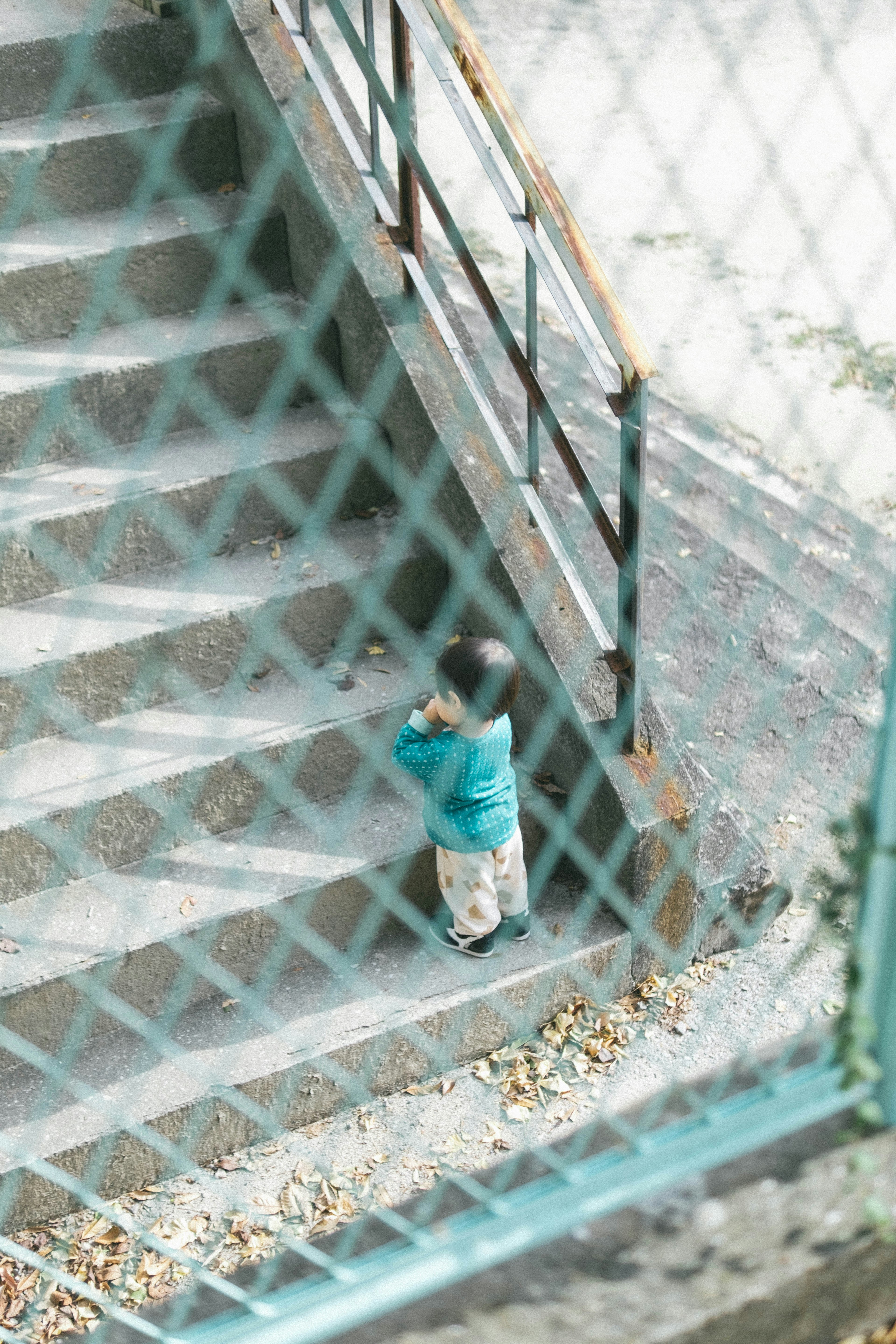 Child climbing stairs seen through a fence