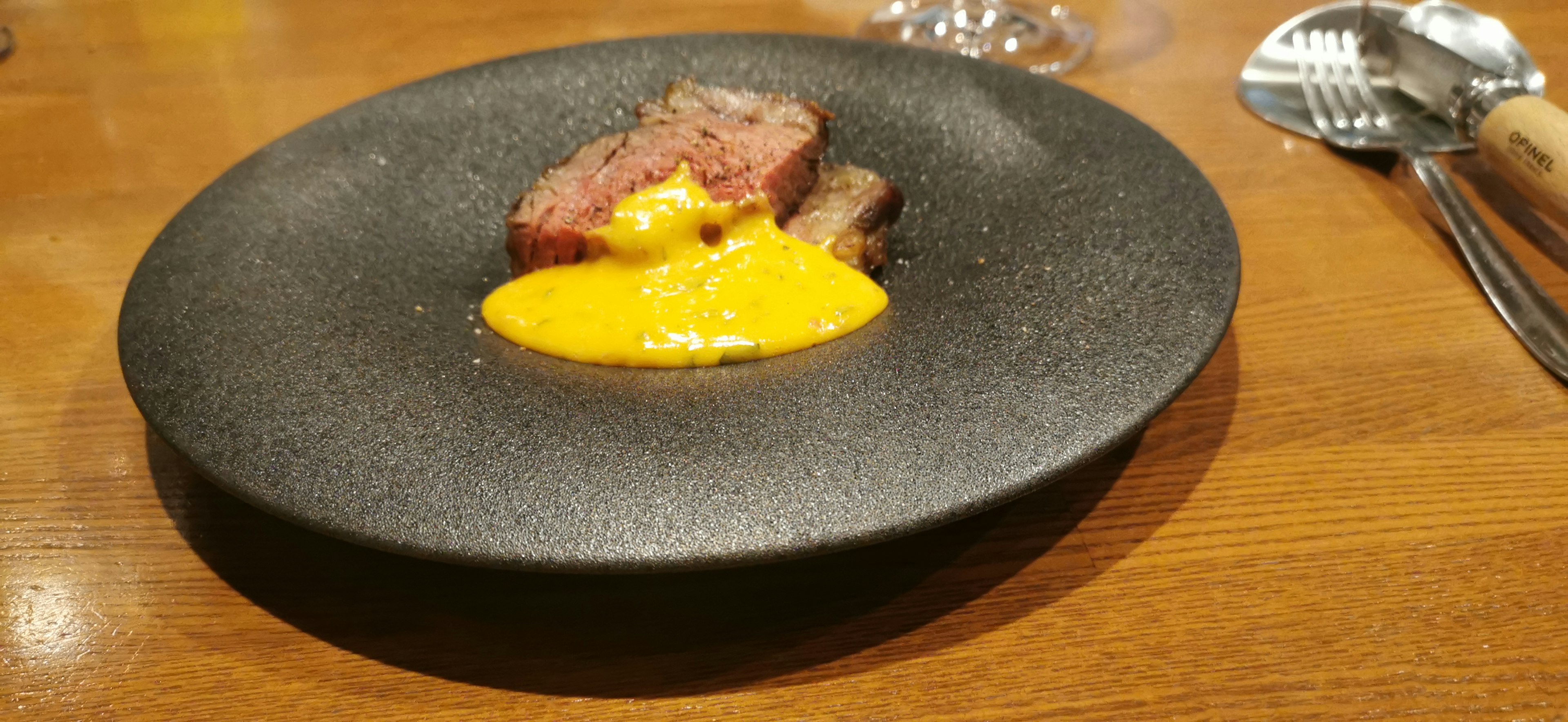 Sliced meat with orange sauce on a black plate