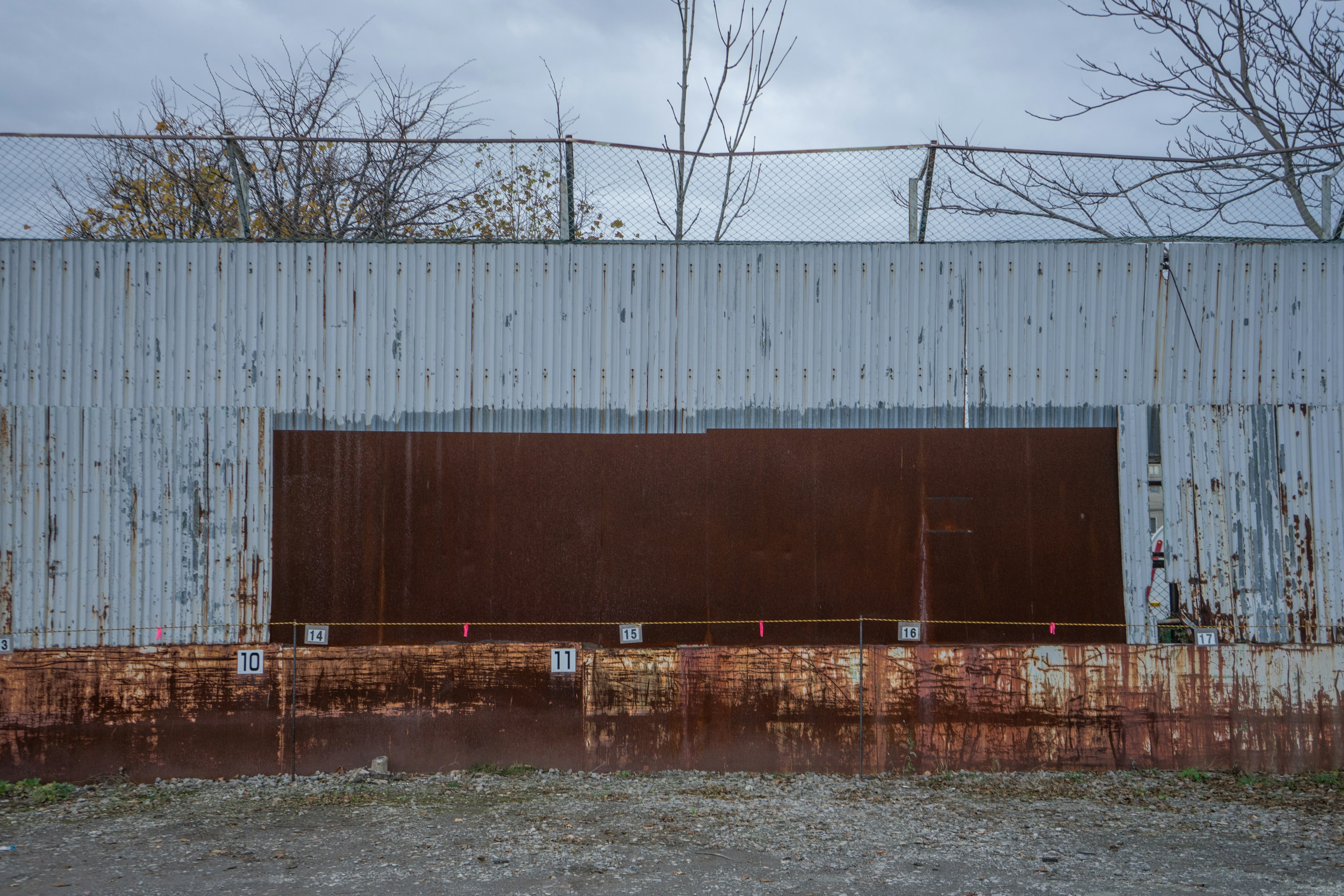 Industrial scene featuring a rusty metal wall with a brown door in the center