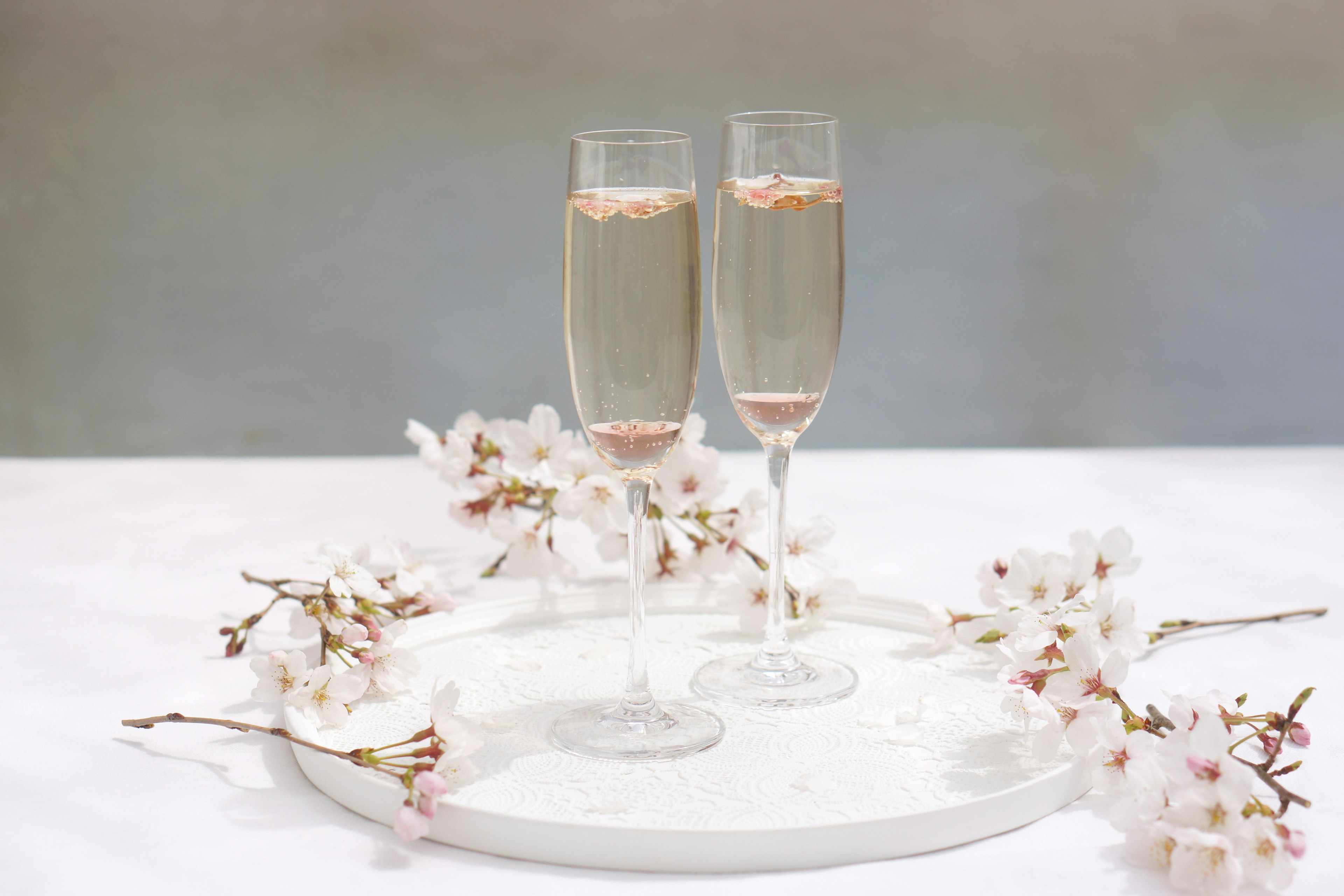 Impostazione elegante della tavola con bicchieri di champagne e fiori di ciliegio