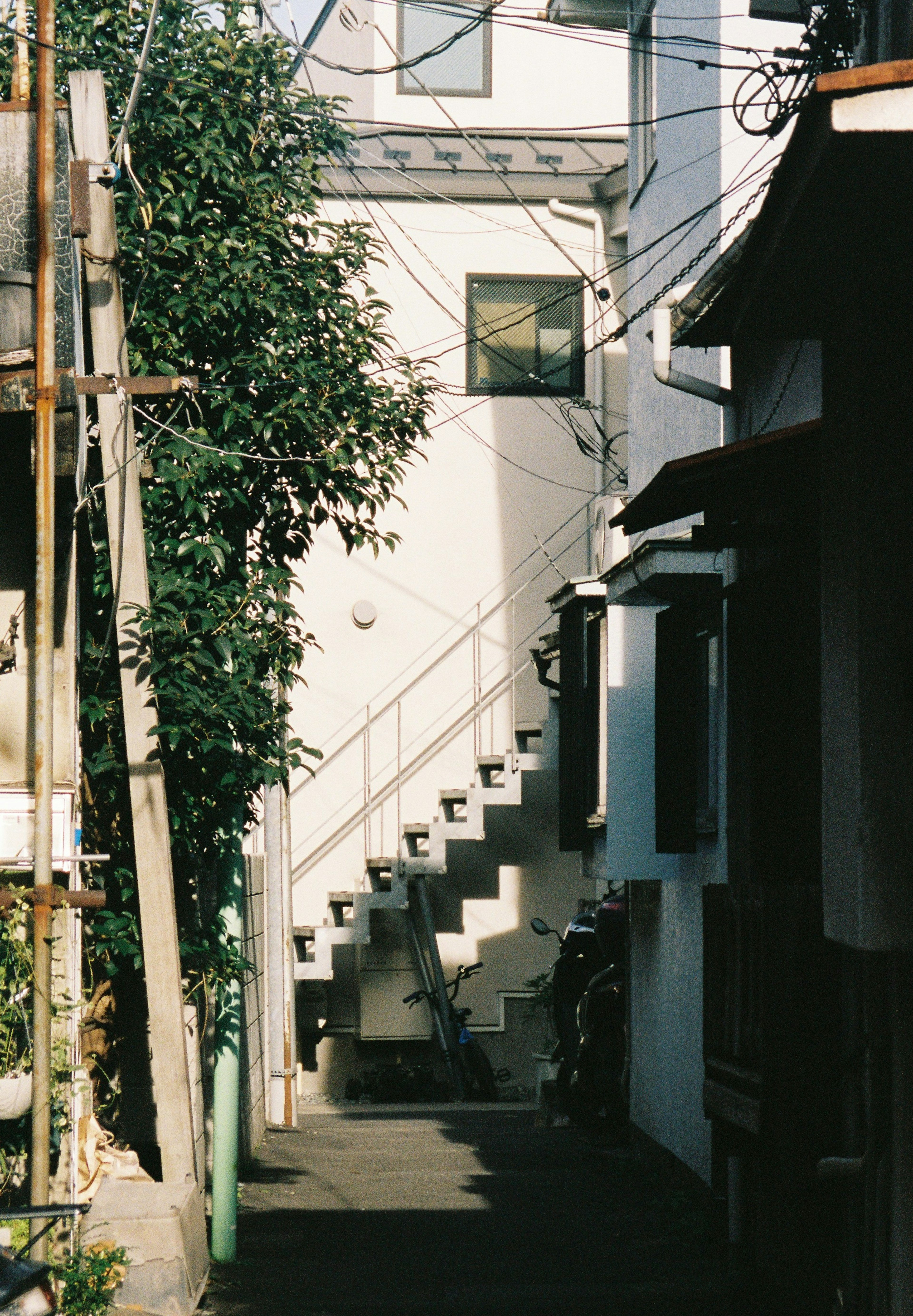 Lorong sempit dengan bangunan putih dan bayangan tangga