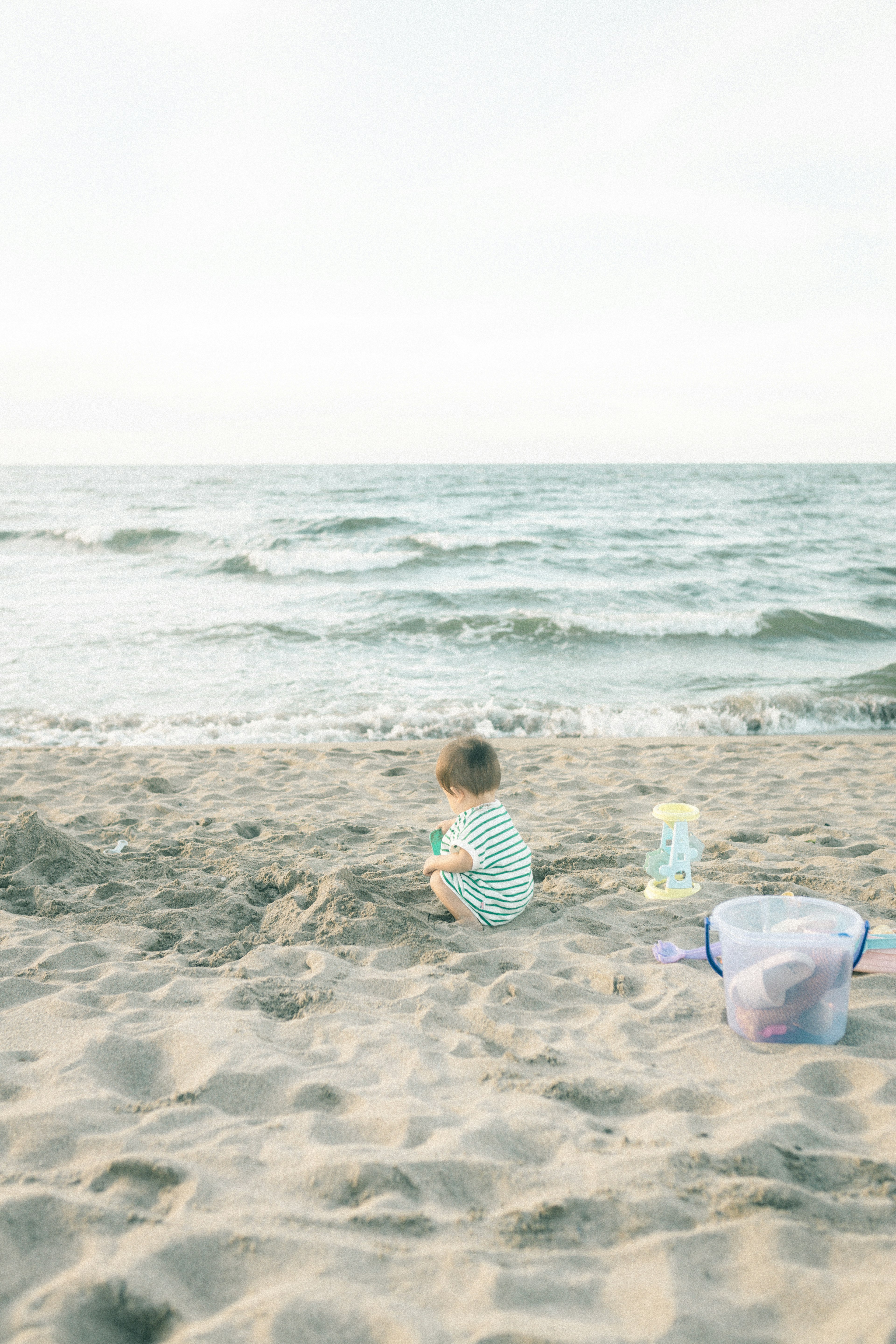 Anak bermain di pantai dengan ombak di latar belakang