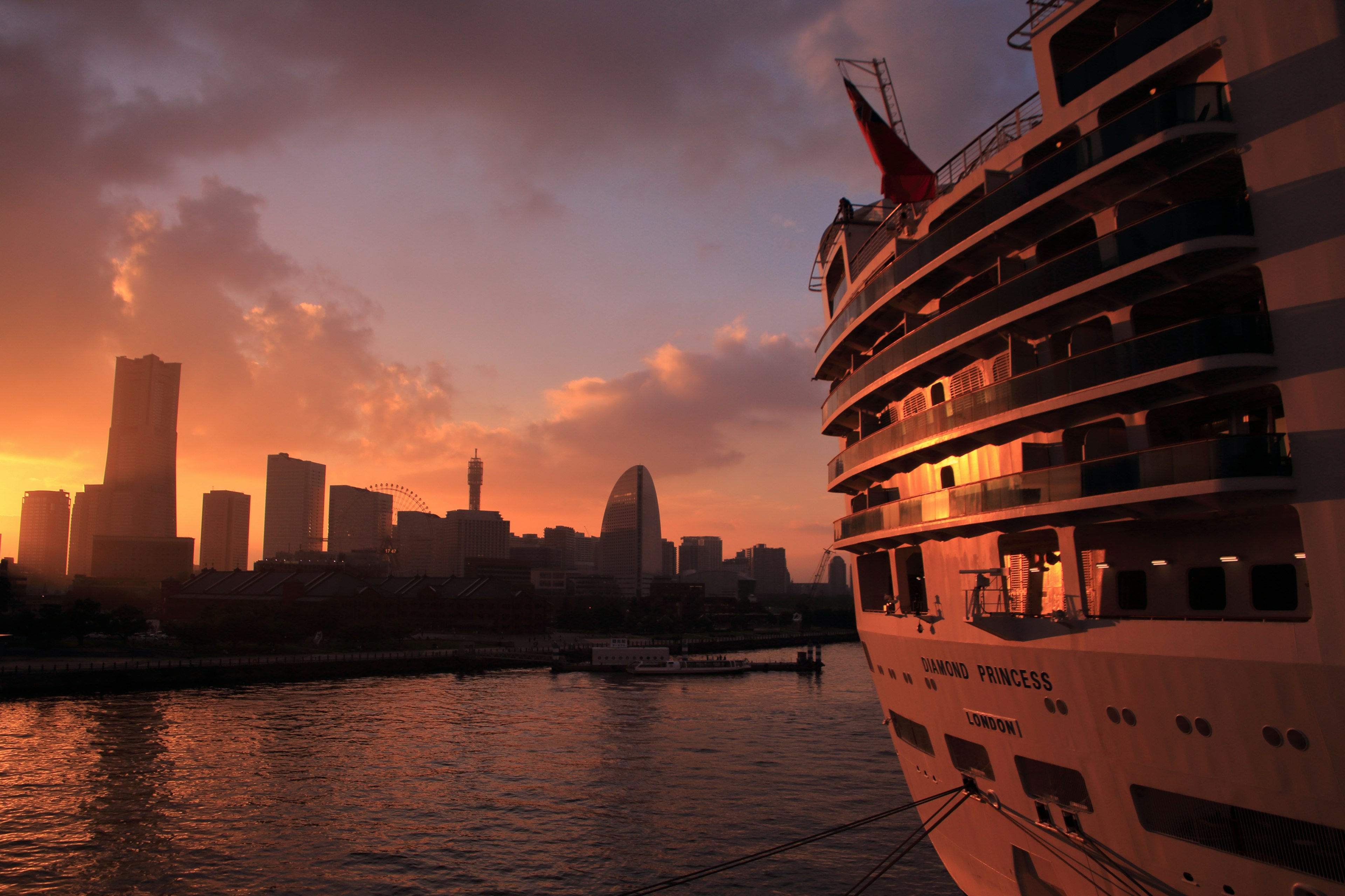 Nave da crociera silhouette contro un vivace tramonto con skyline cittadino