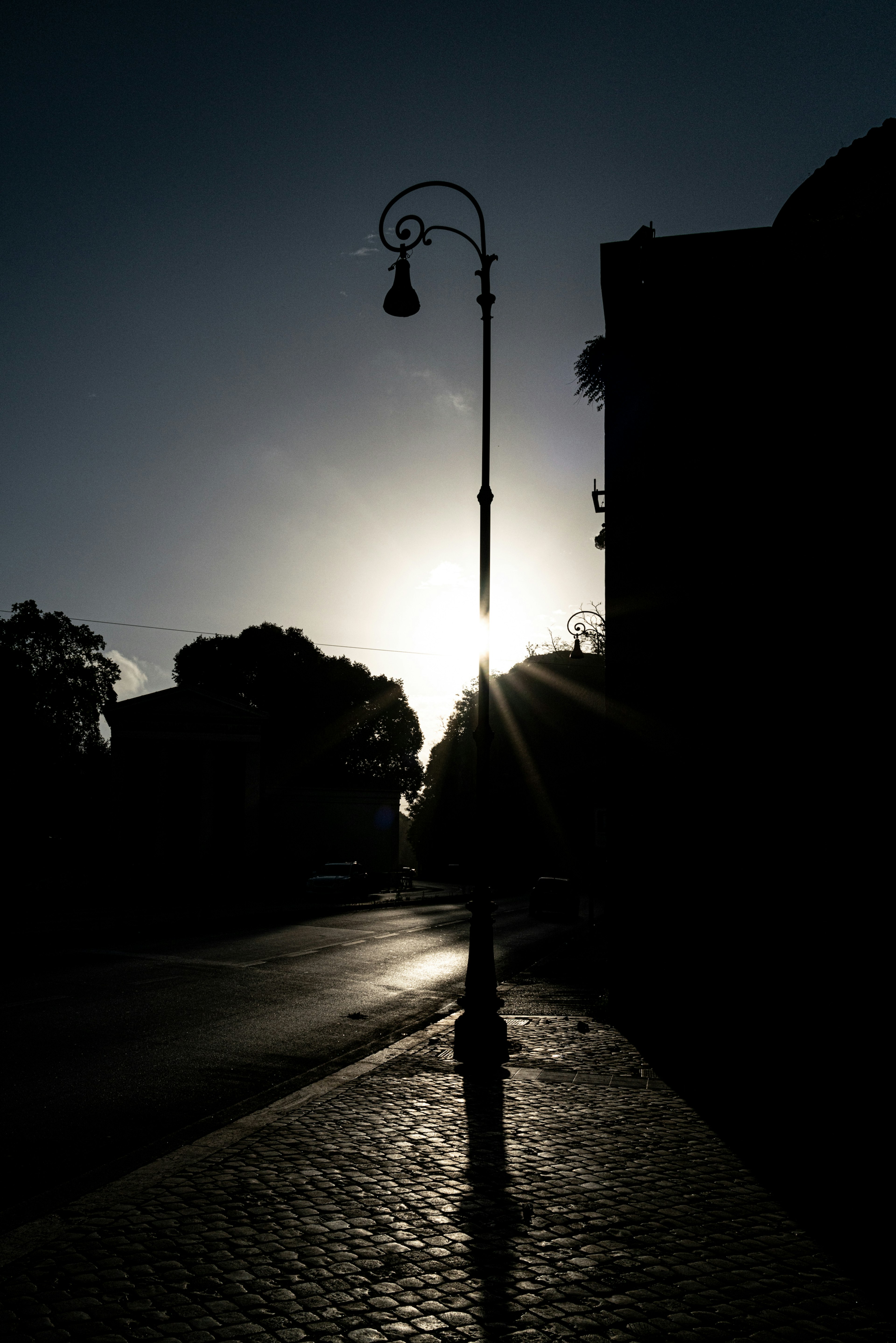 Silhouette of a street lamp against the backdrop of the sun at dusk