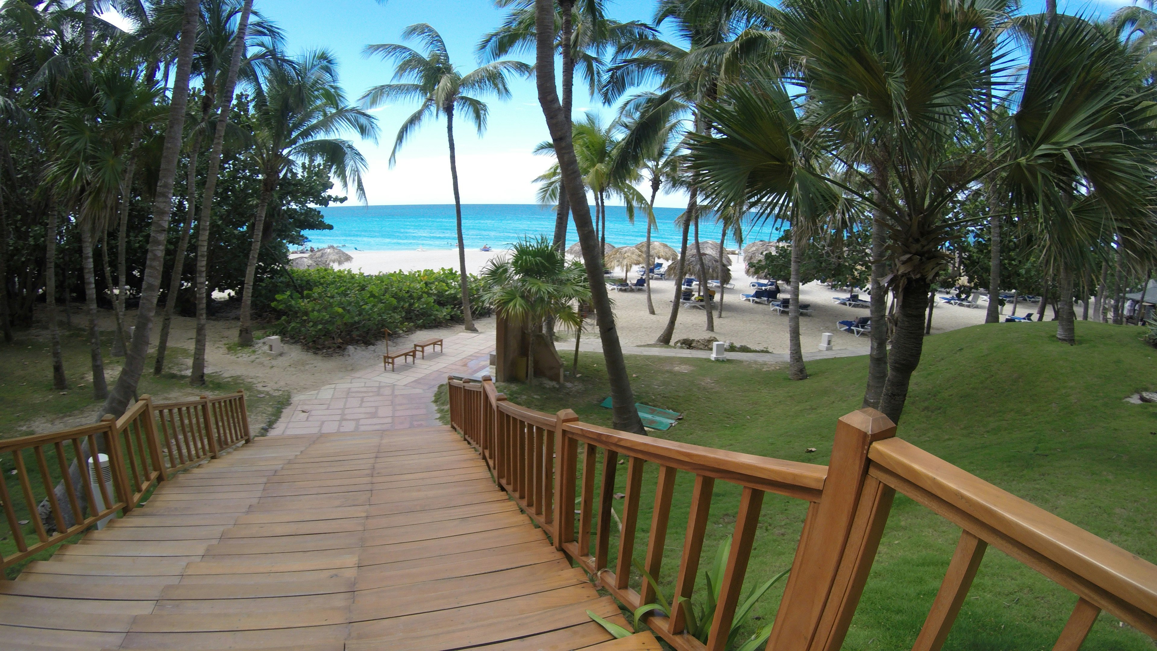 Wooden staircase leading to a tropical beach with blue ocean and white sand