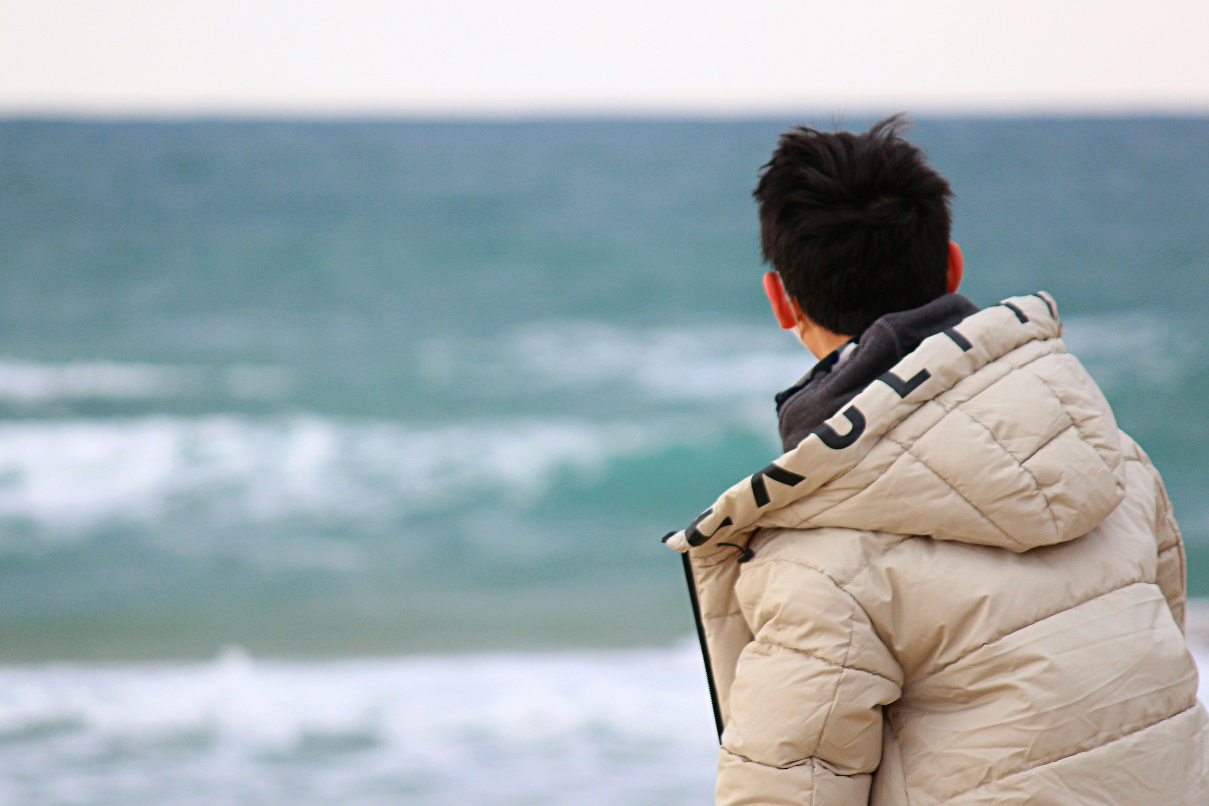 Person, die von hinten auf das Meer schaut