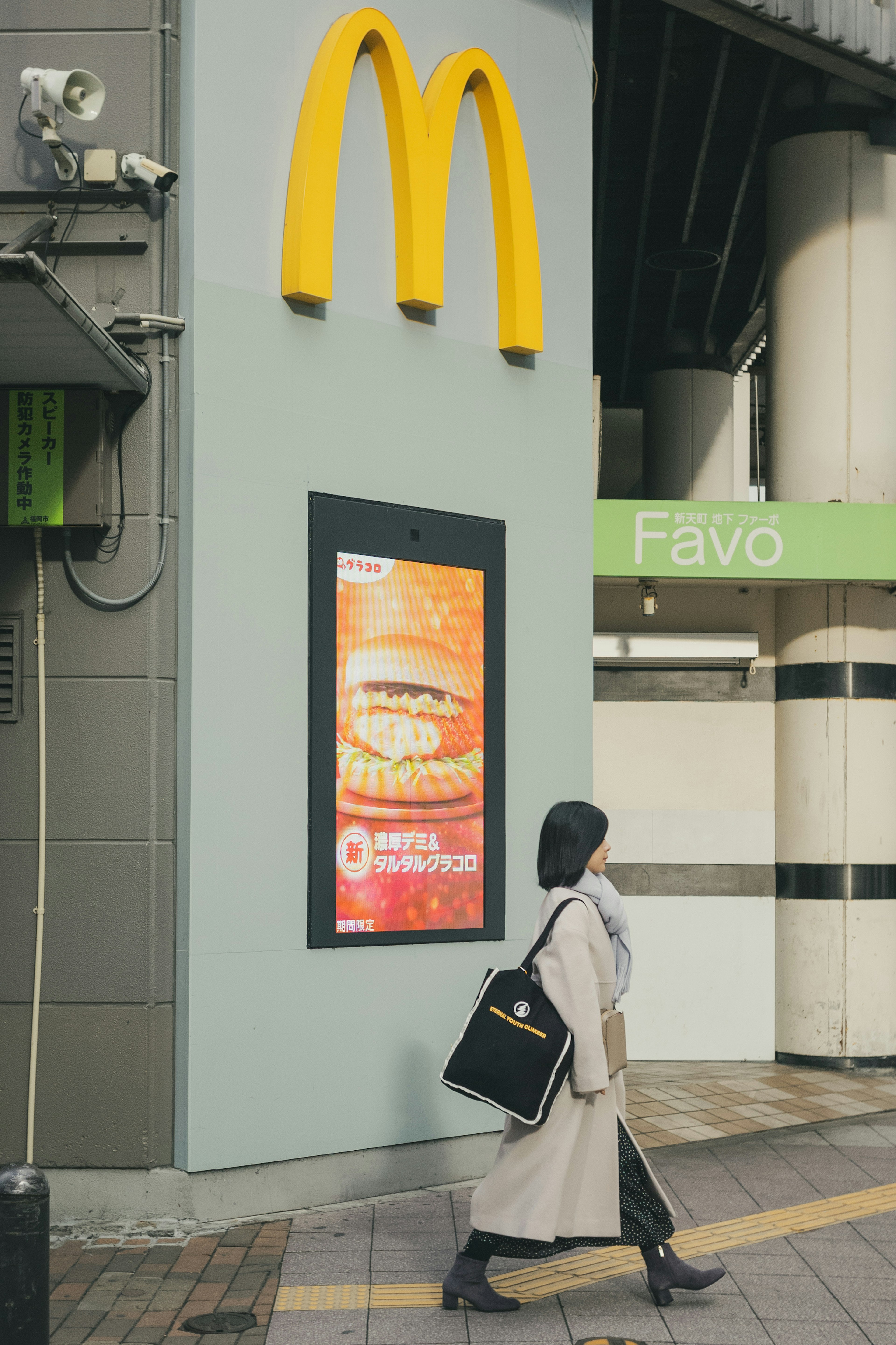 Seorang wanita berjalan di depan papan tanda McDonald's