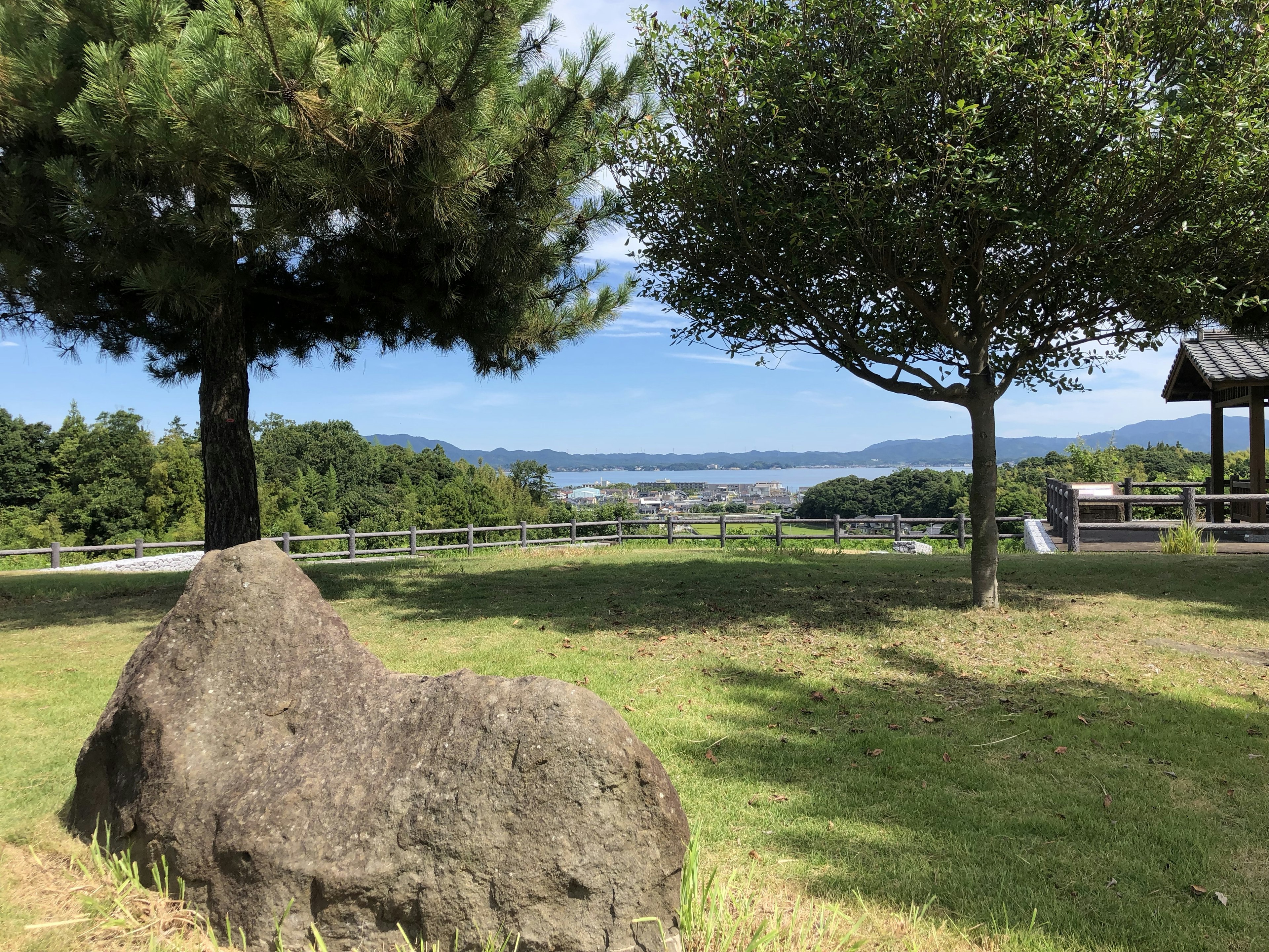 Large rock in a park with two trees and a distant landscape