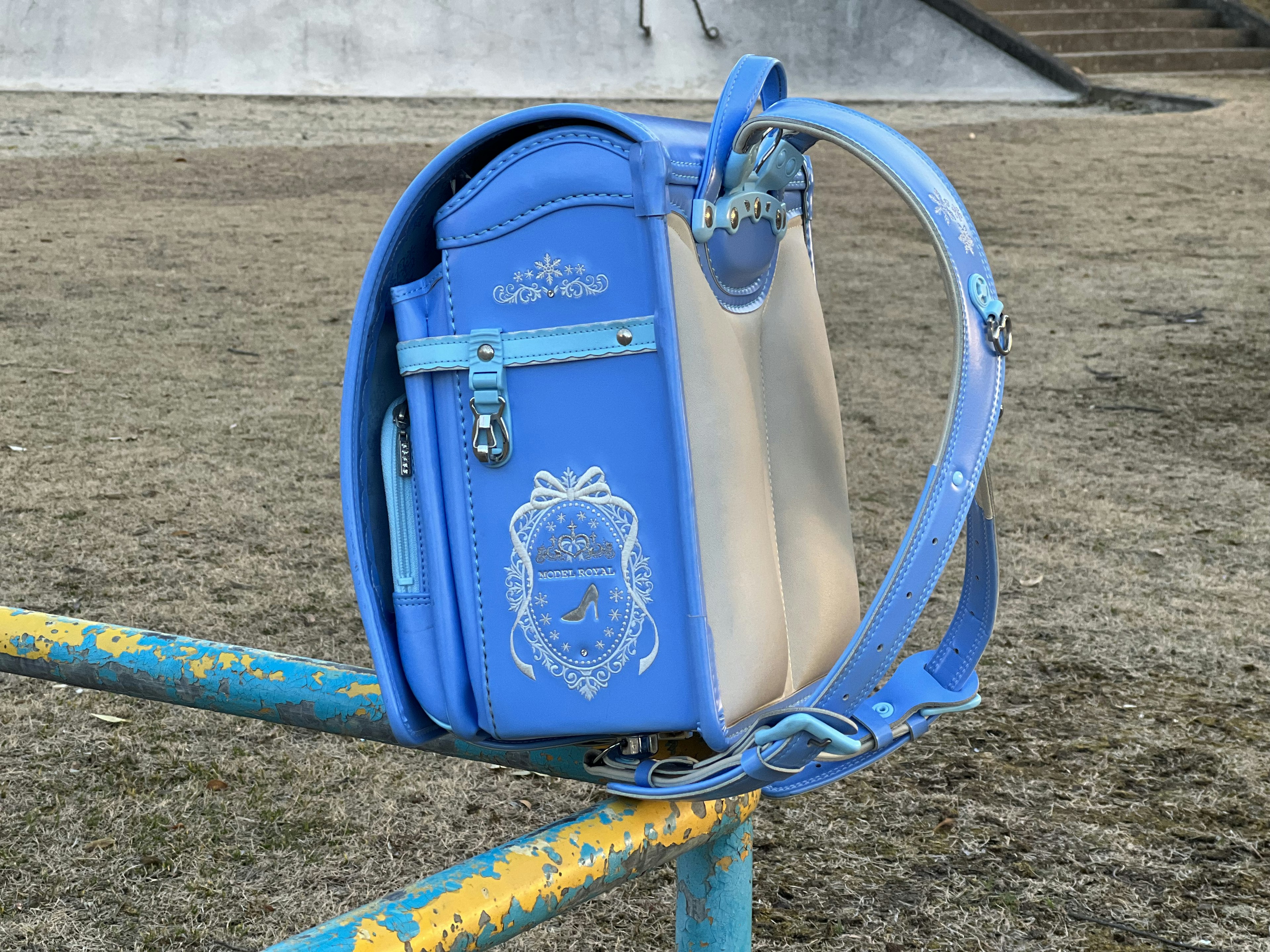 A blue backpack hanging on a metal bar