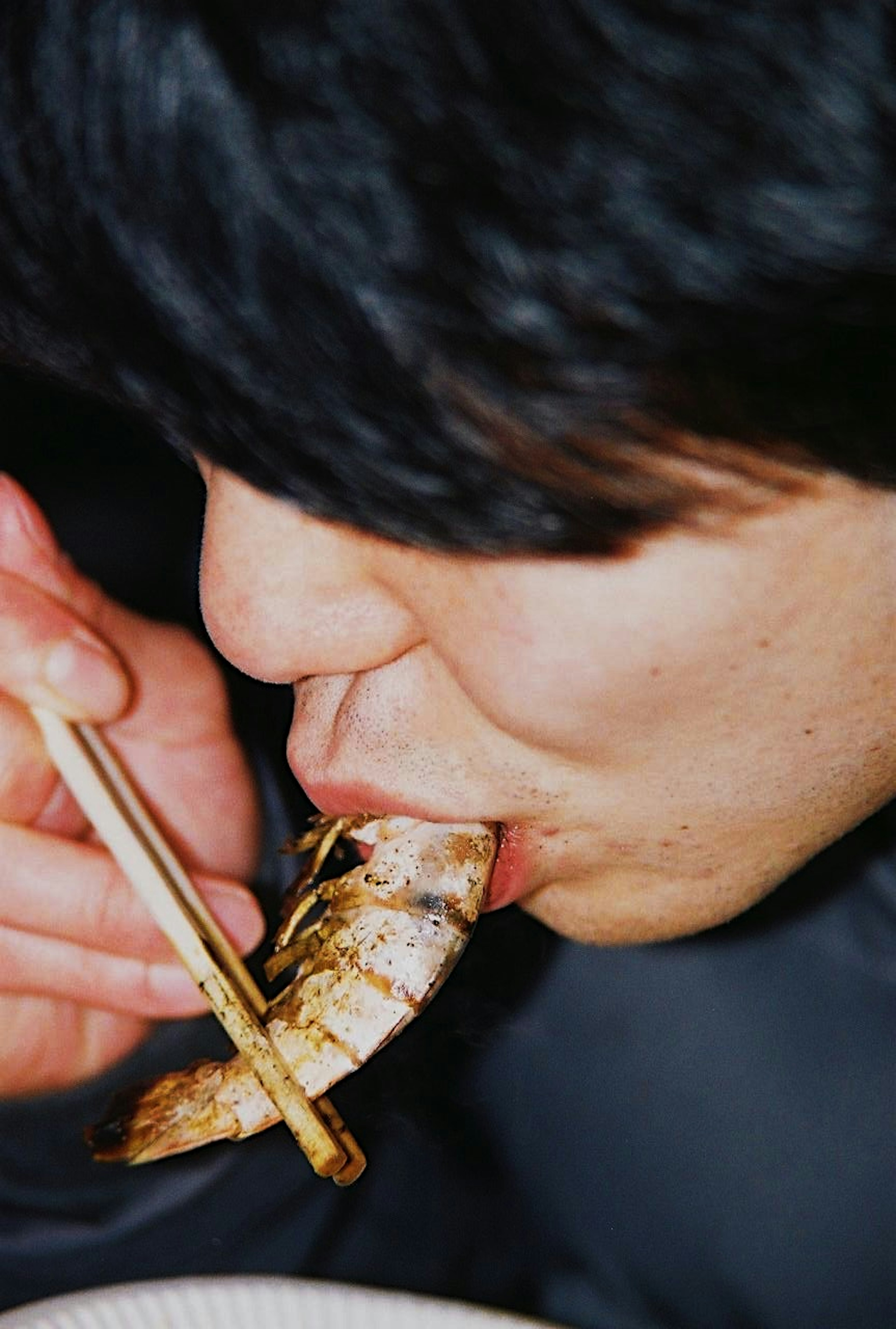 Un homme utilisant des baguettes pour manger des crevettes