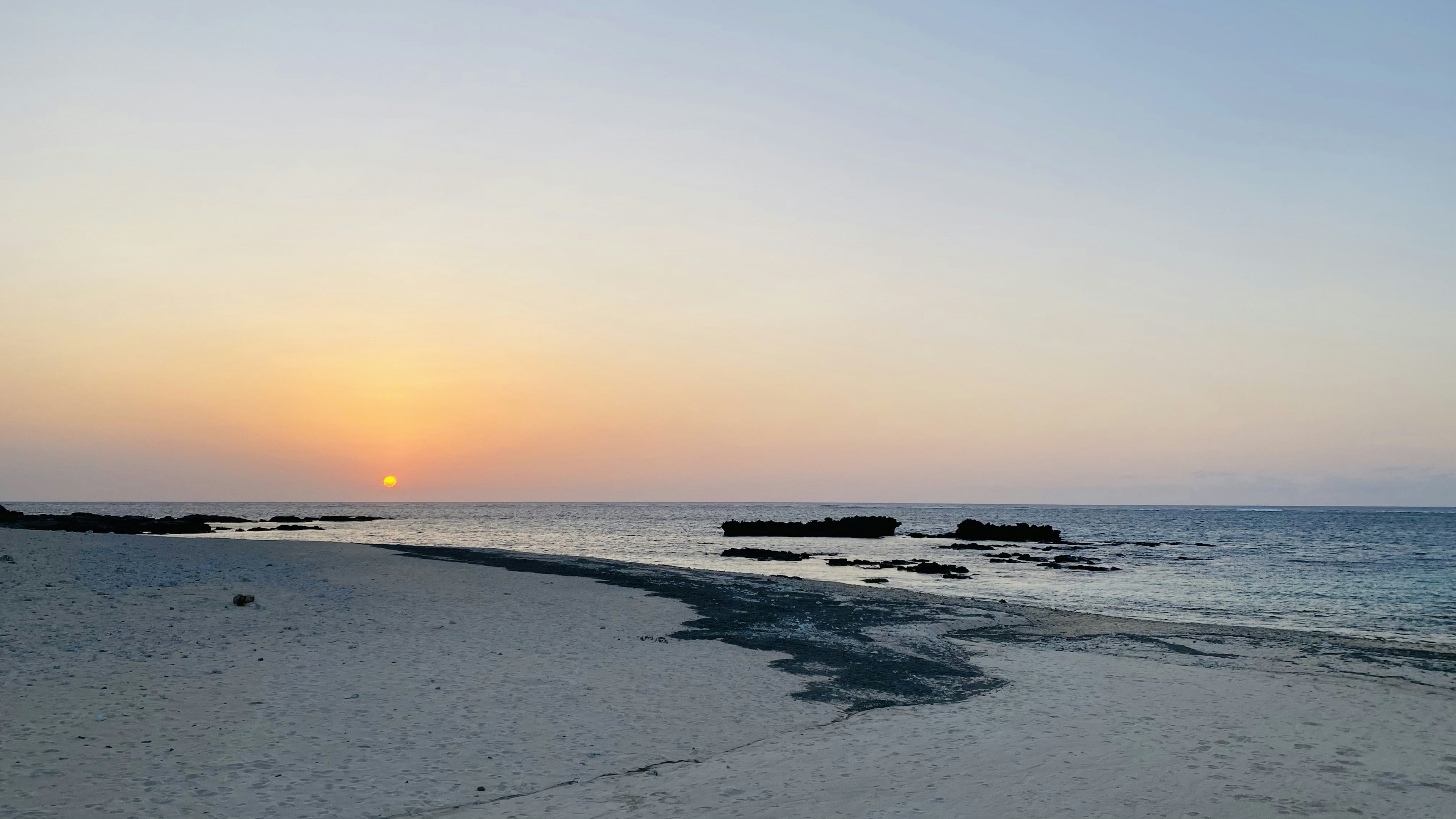 静かなビーチに沈む夕日と穏やかな海の風景