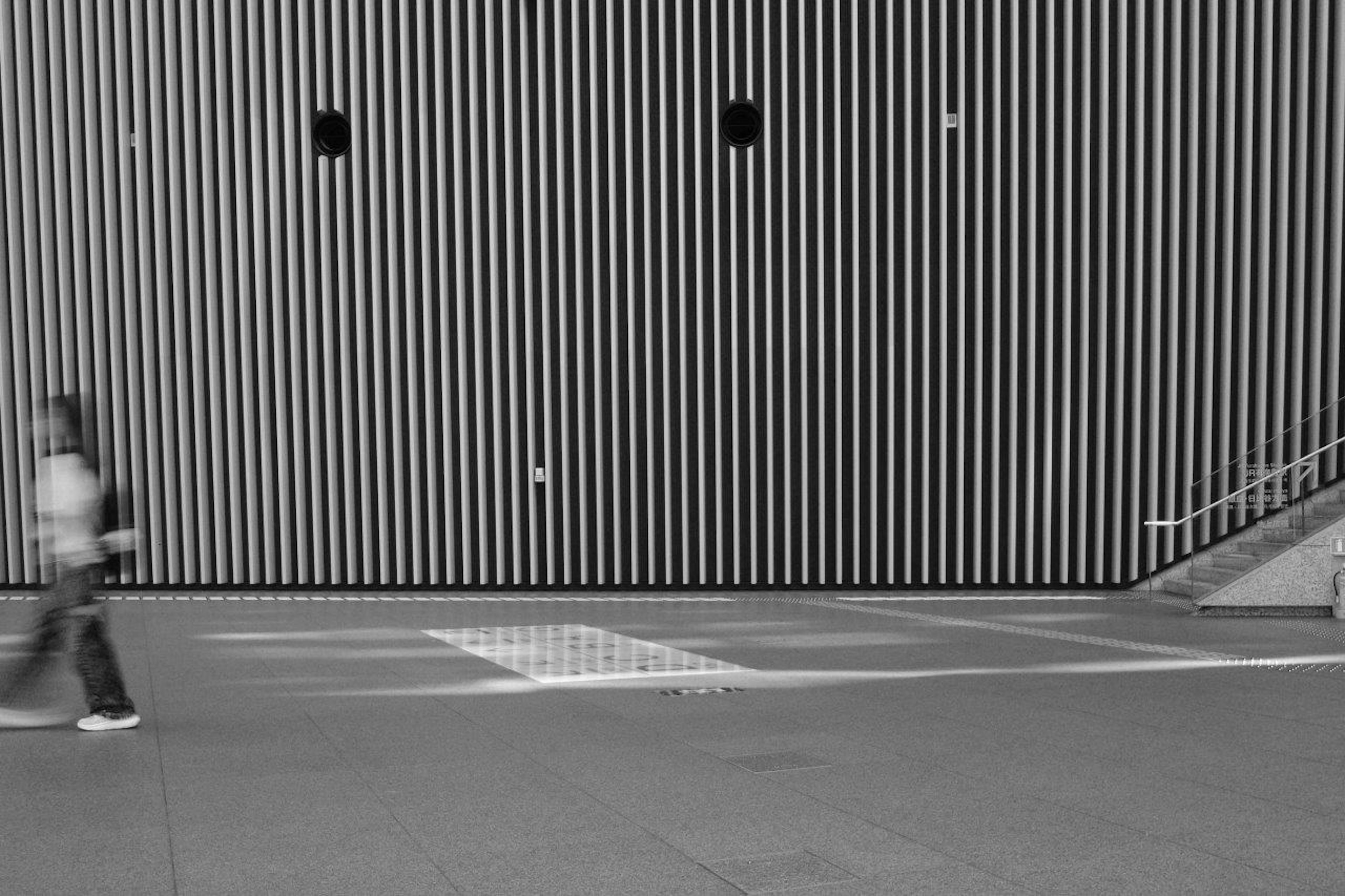 Persona caminando frente a una pared de rayas blancas y negras