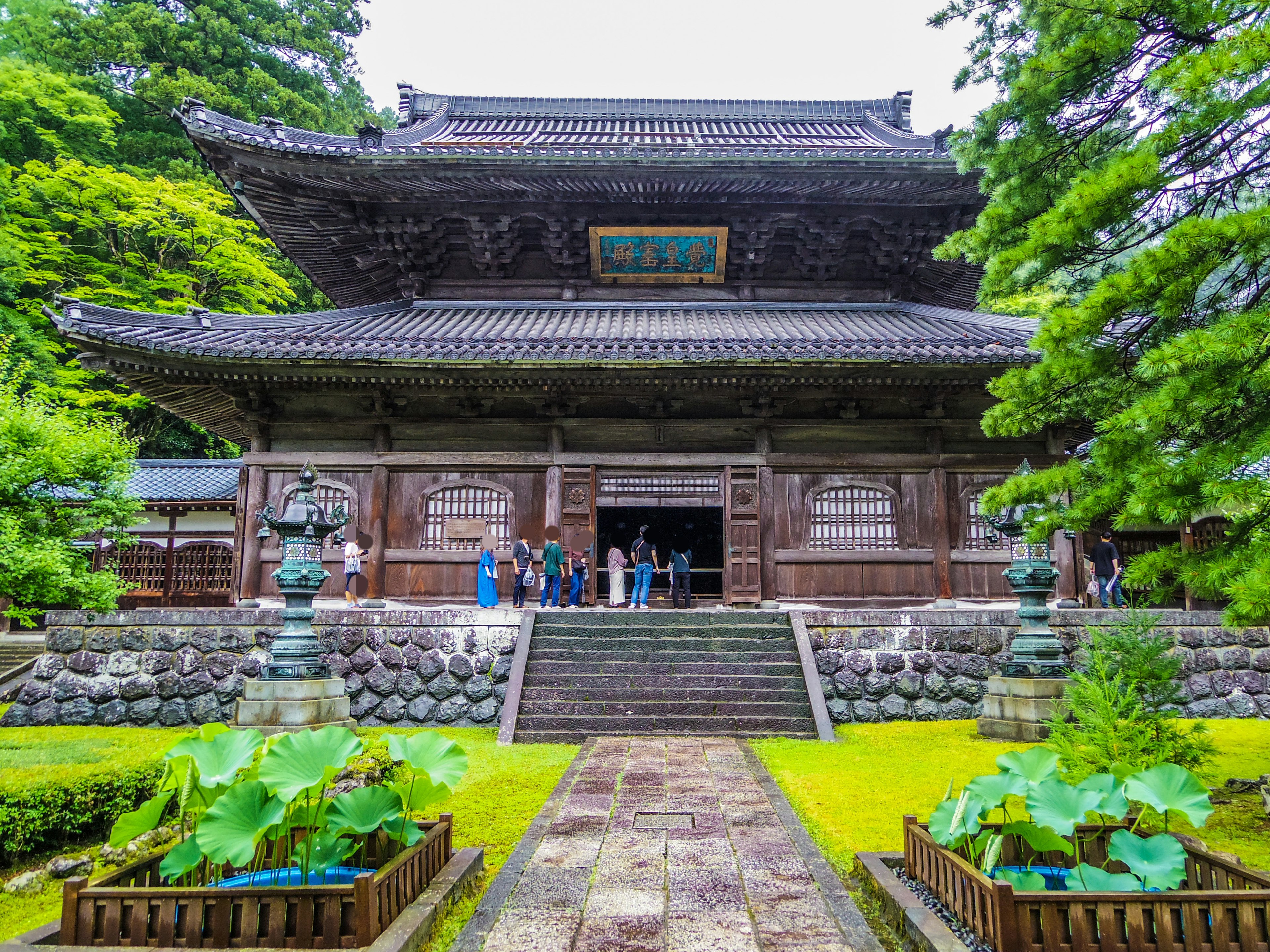 Belle façade de temple japonais avec des jardins luxuriants et des escaliers en pierre