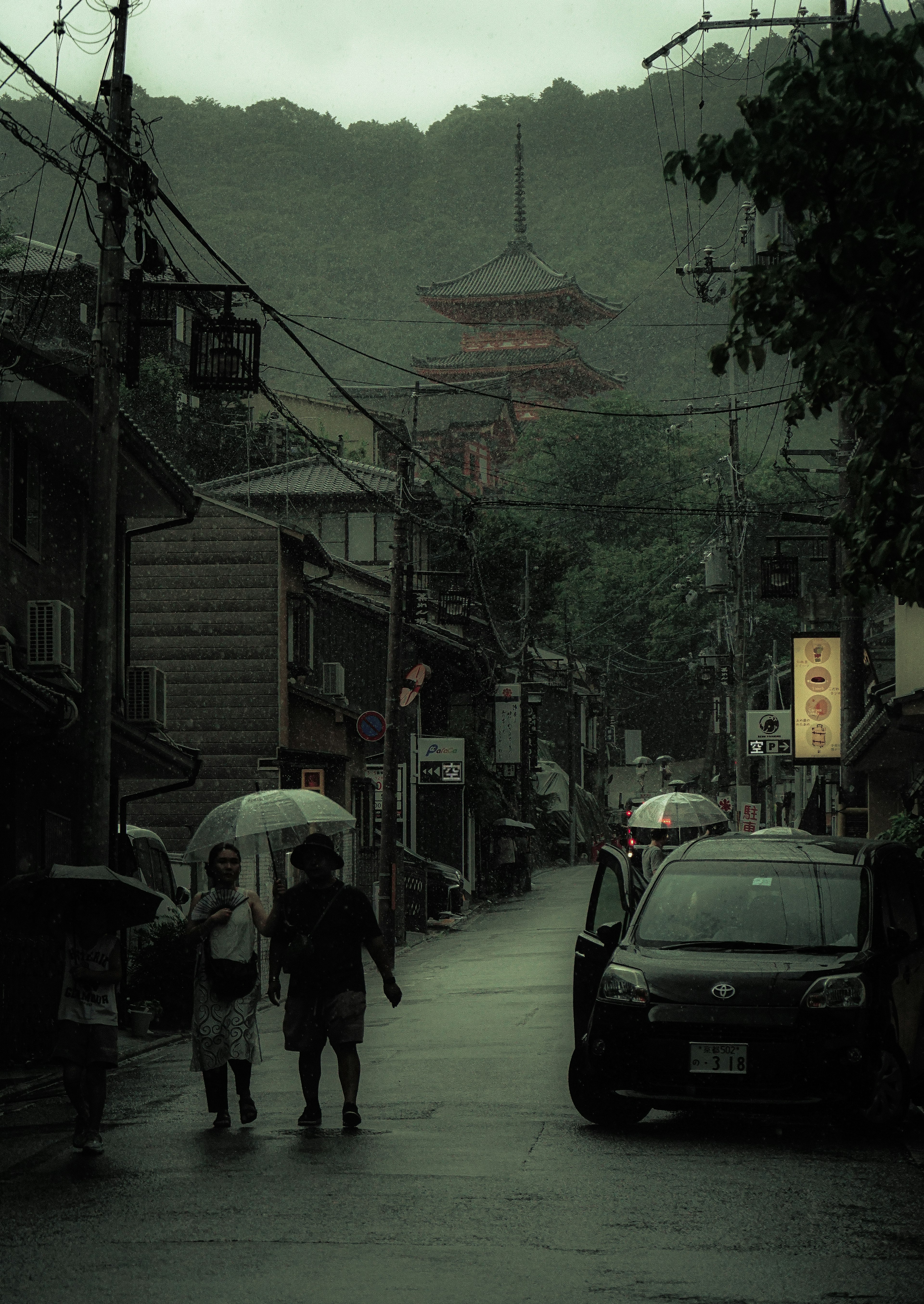 雨の中で歩く人々と背景の塔が見える街の風景