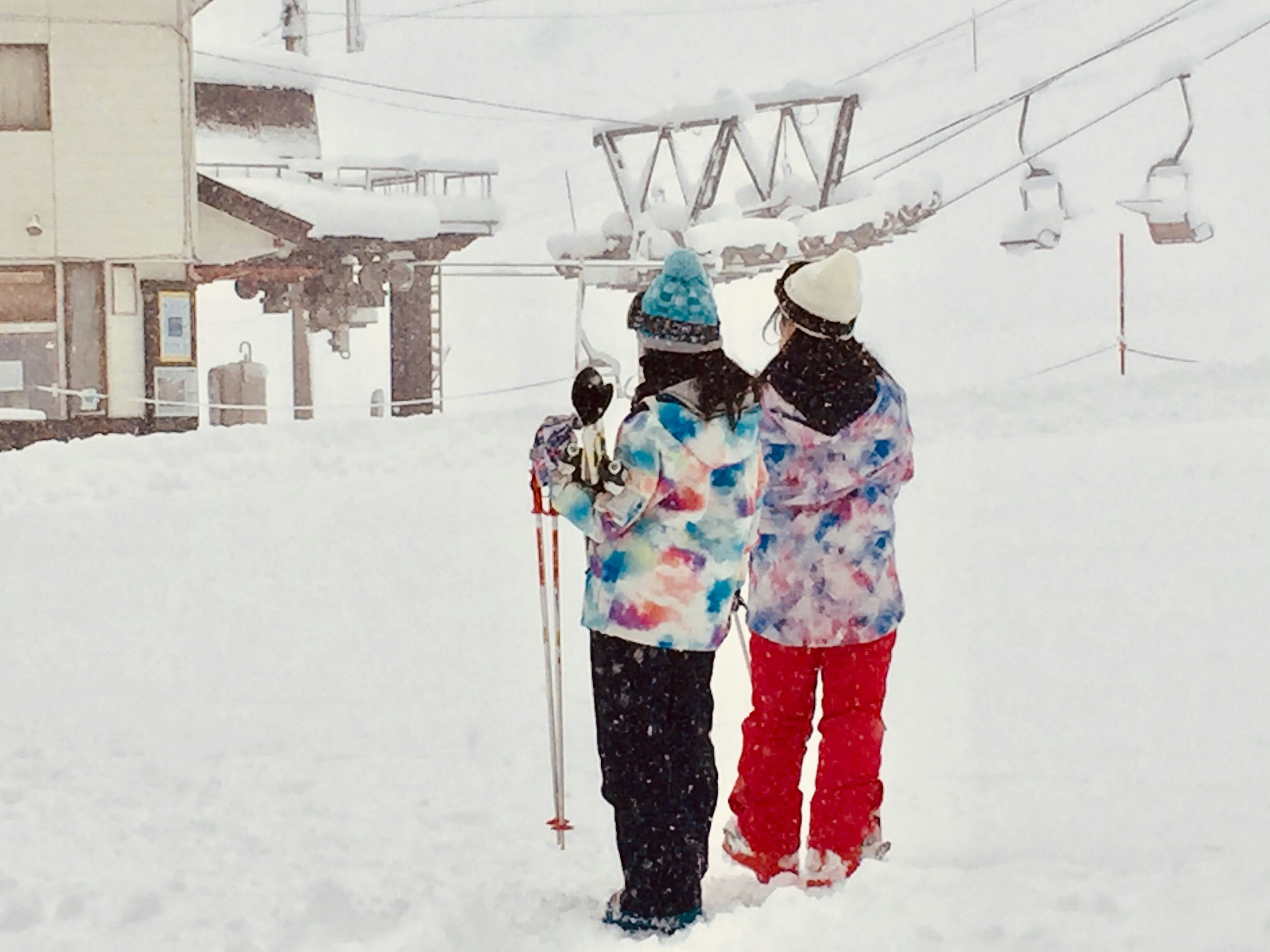 雪の中でスキーを待つ二人の女性 colorful jackets