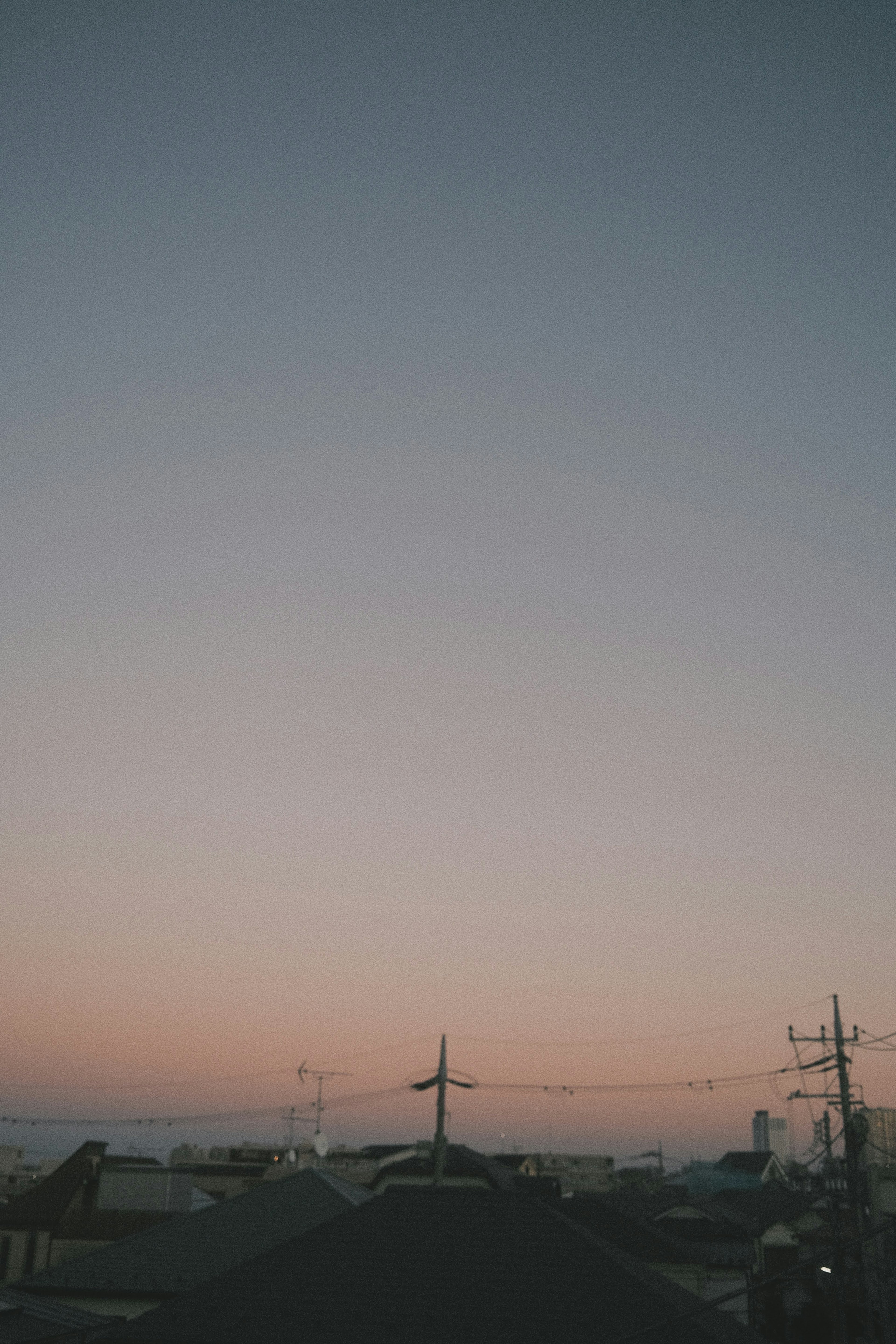 Cielo al atardecer con líneas eléctricas y techos