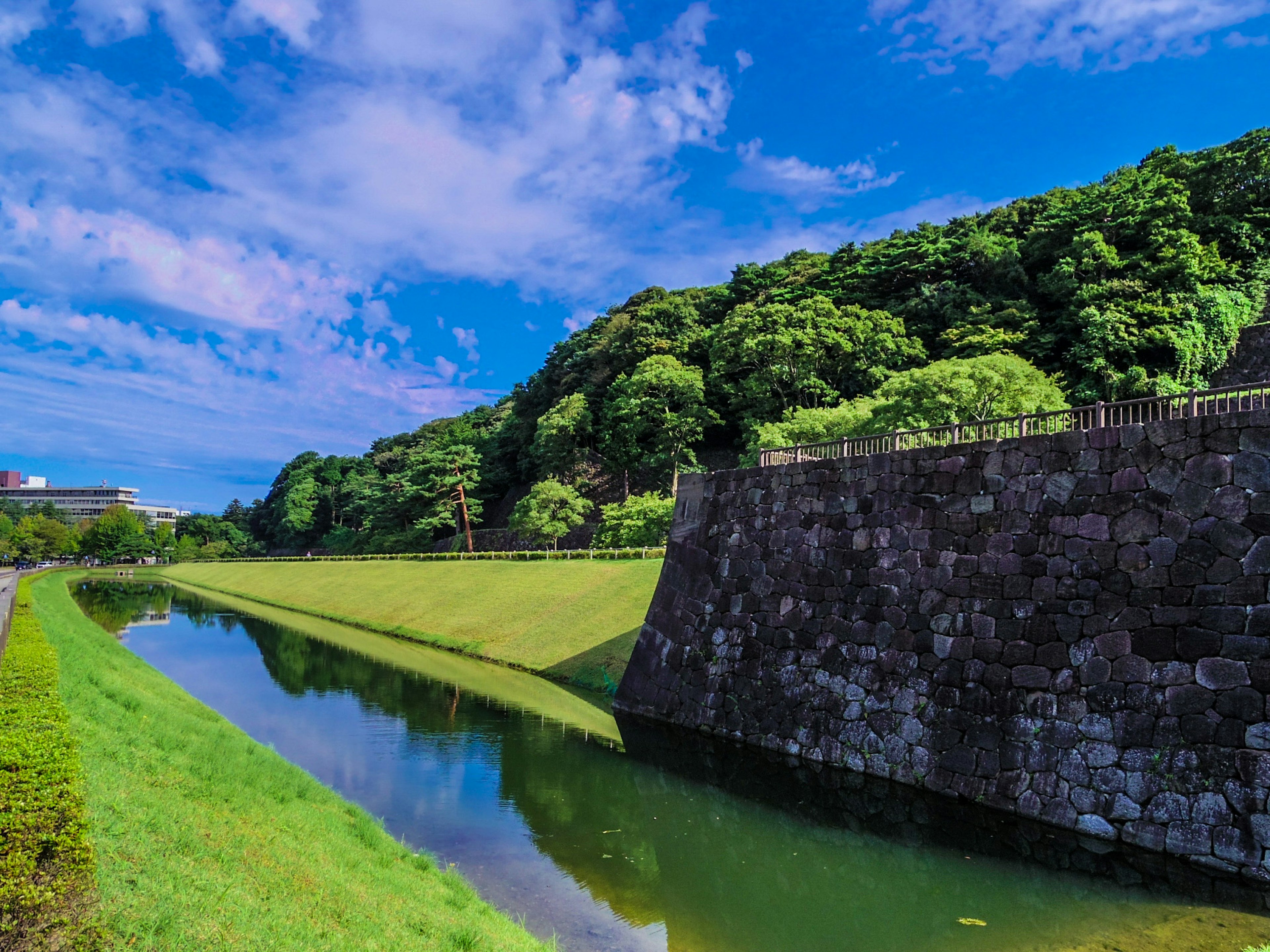 Lush green hillside and stone moat under a blue sky