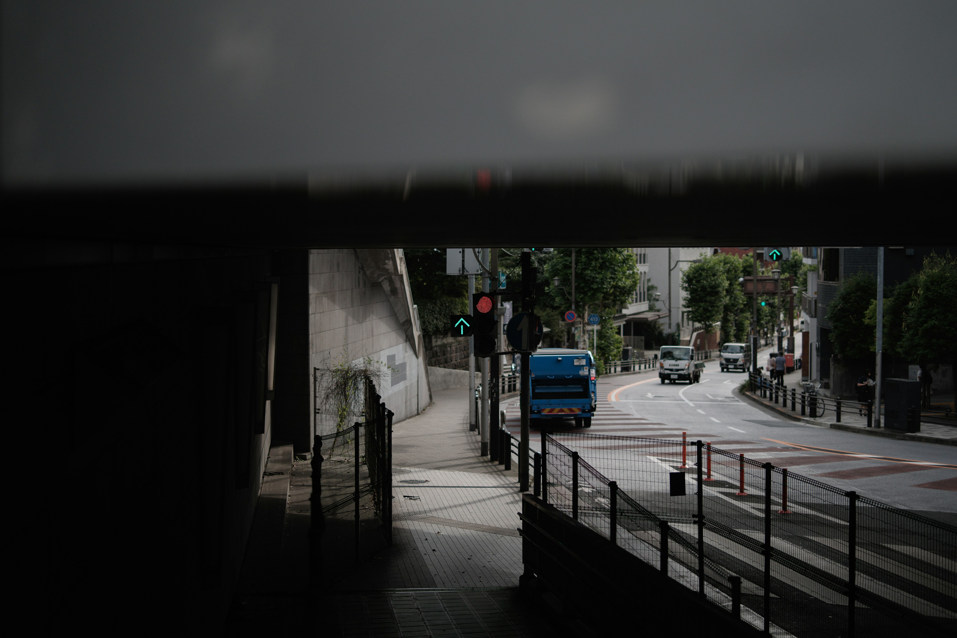 Urban scene viewed from a tunnel exit showing a street with vehicles and traffic signals