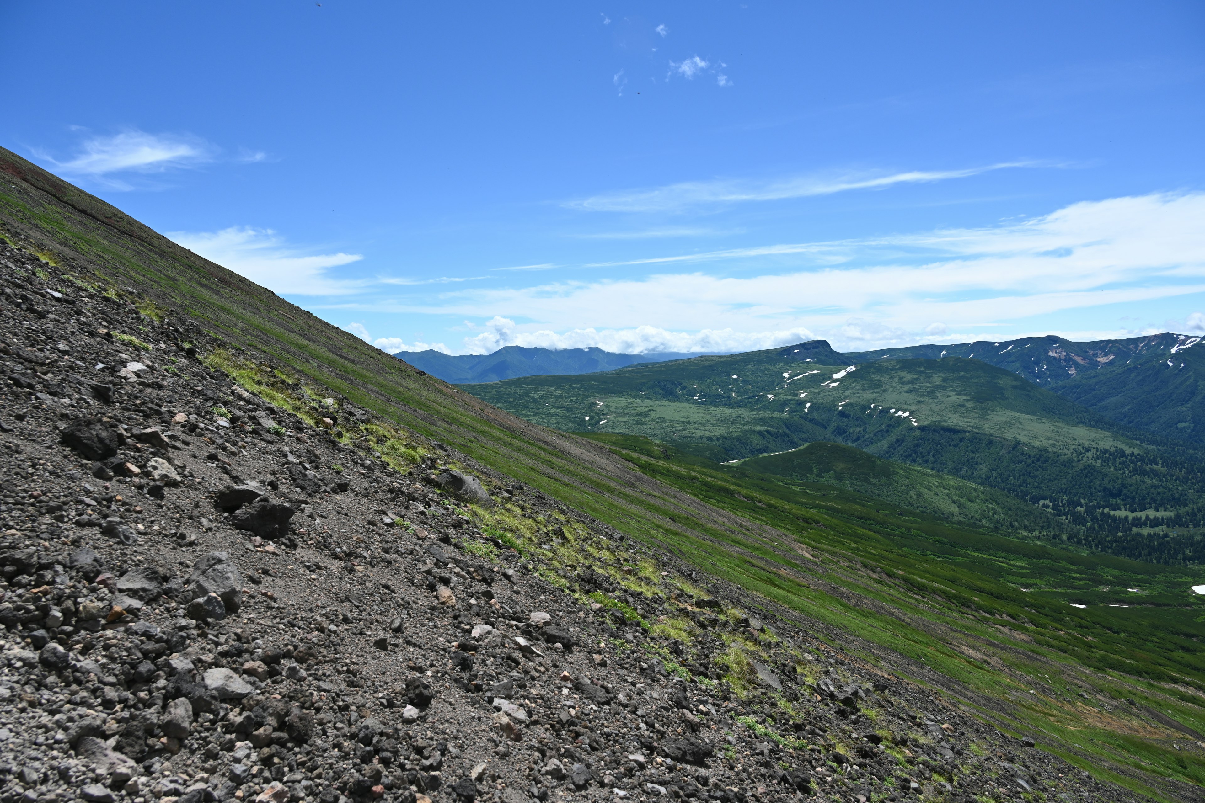 Pente de montagne abrupte avec une vallée verte en arrière-plan