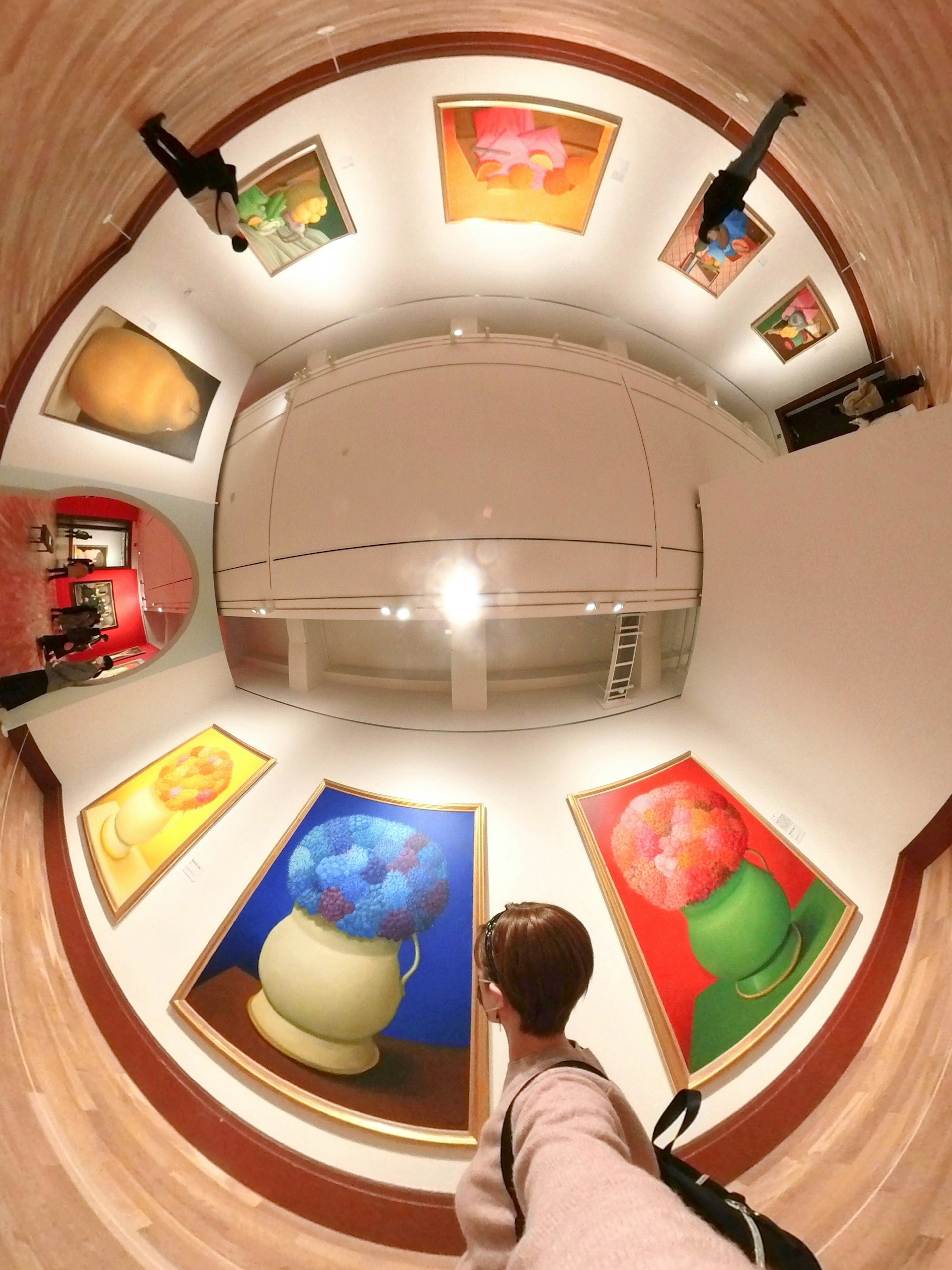 Interior of an art gallery featuring colorful paintings on the walls and a visitor