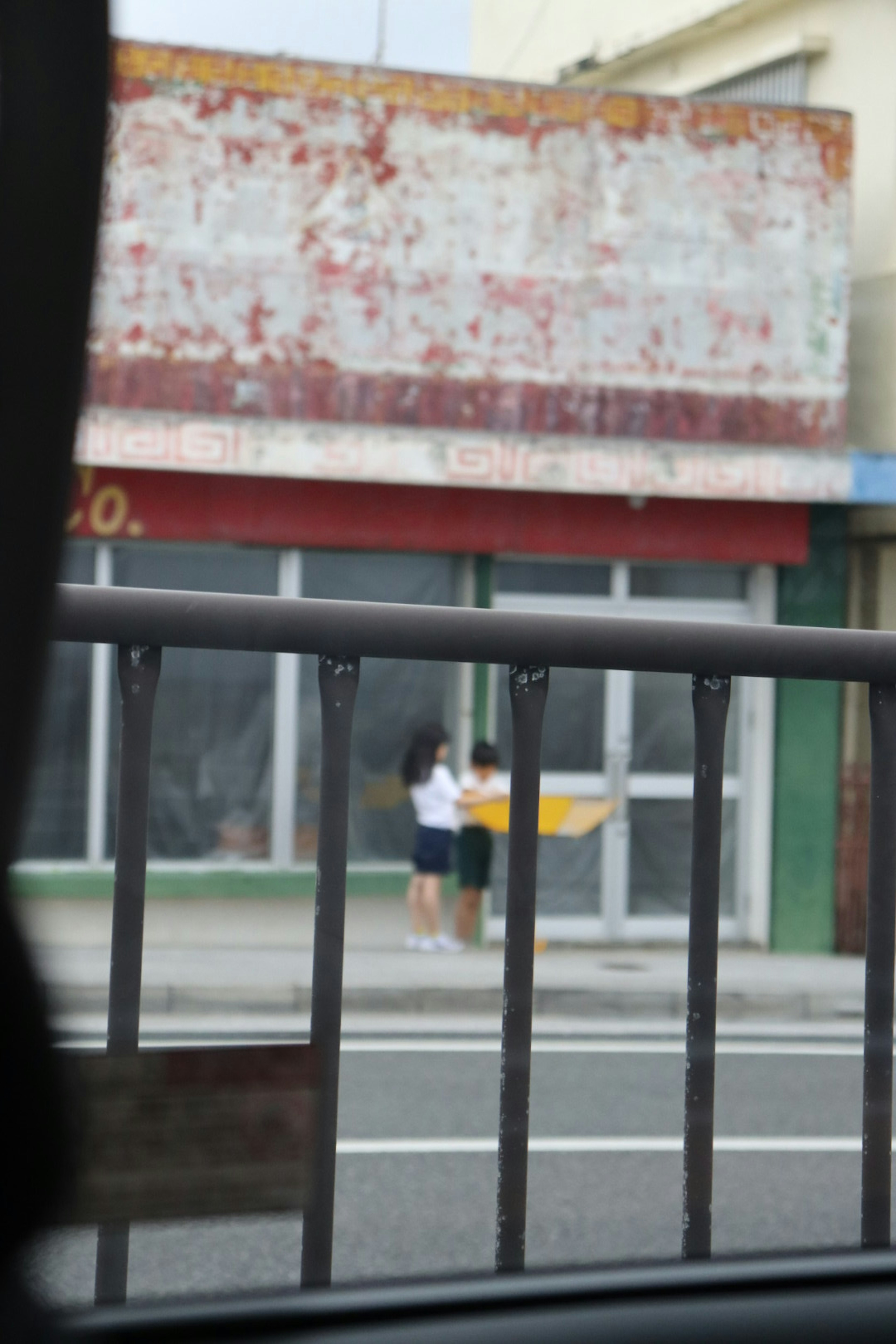 Dos mujeres de pie frente a un edificio antiguo con una cerca oxidada