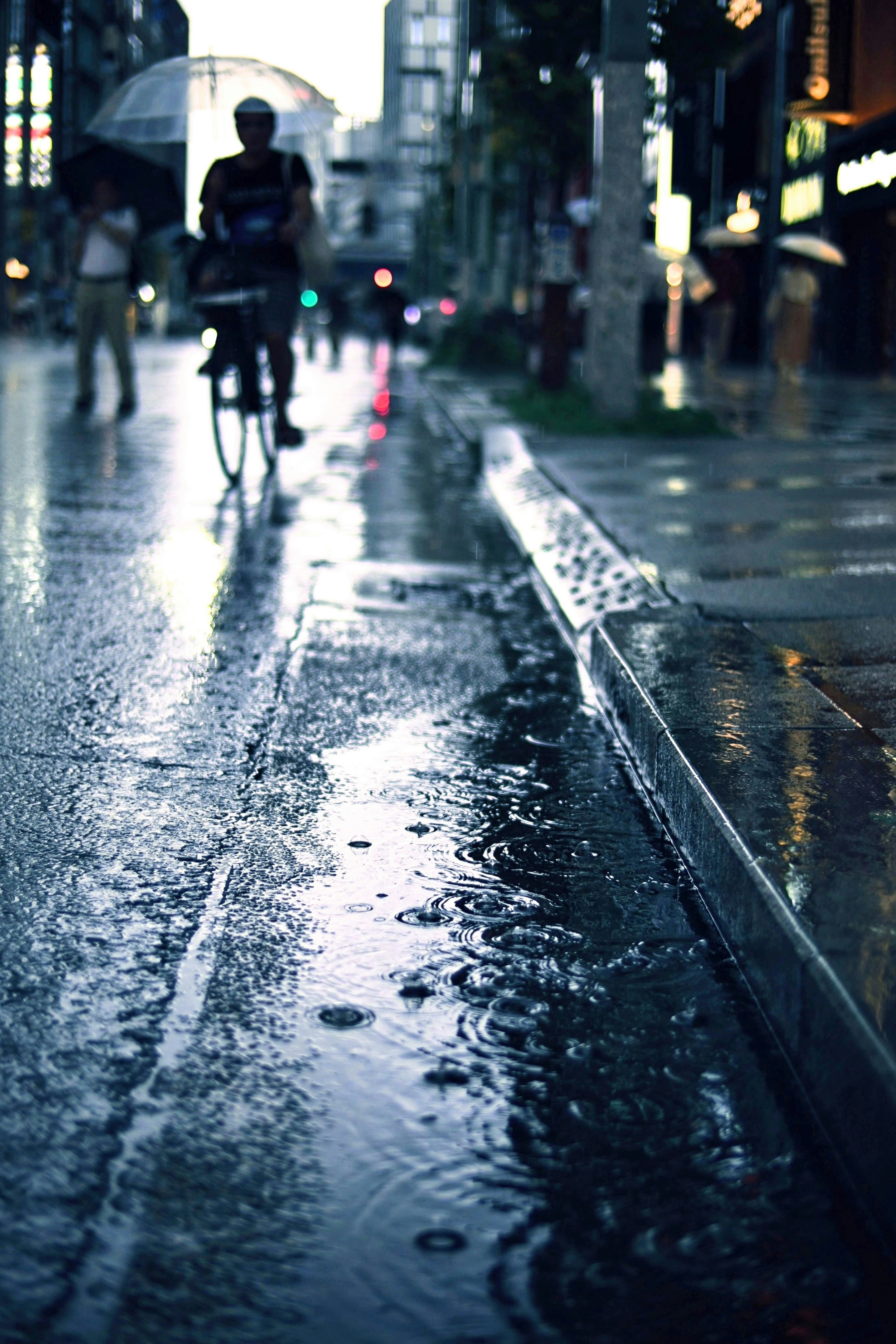 City scene with a person riding a bicycle in the rain