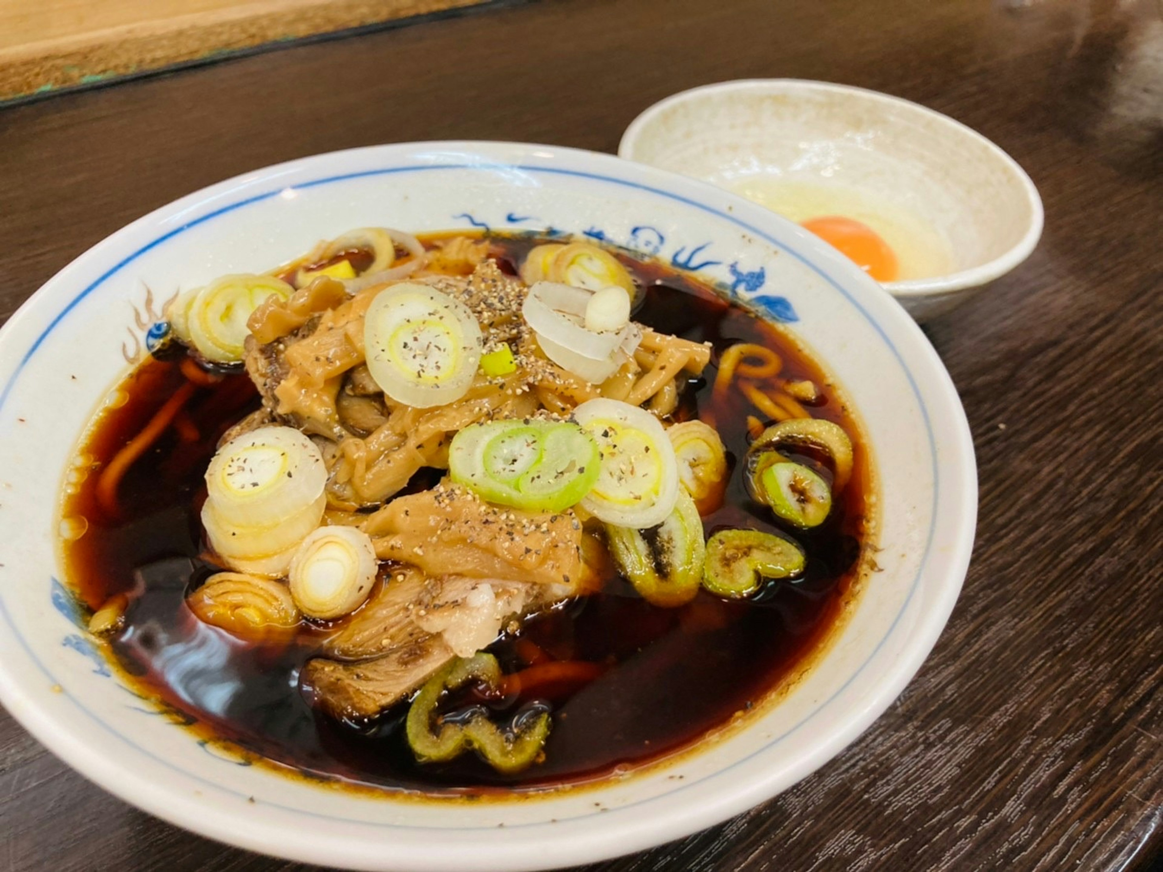 Semangkuk rebusan ayam dan bawang hijau disajikan dengan telur di samping