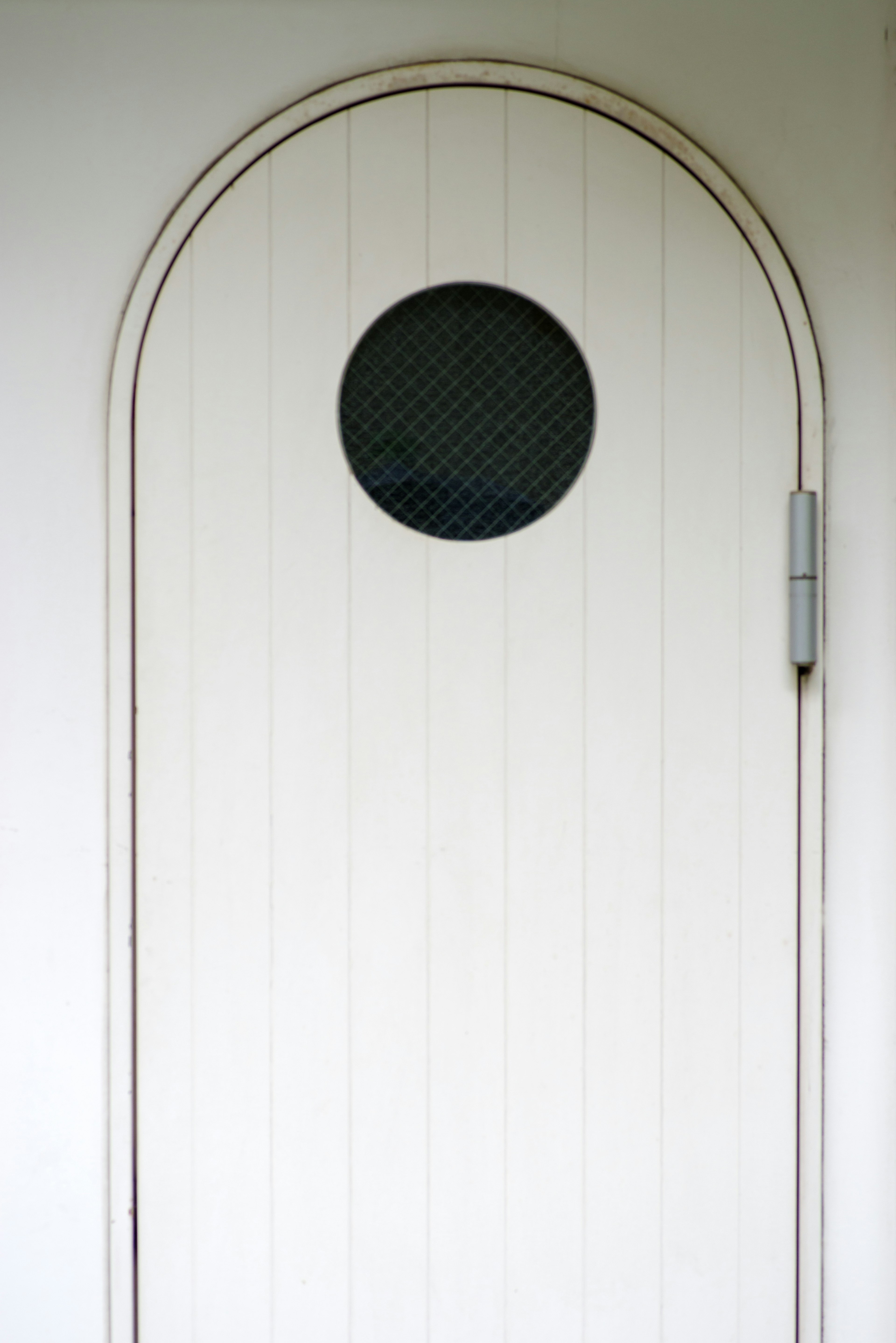 Puerta blanca en arco con una ventana circular