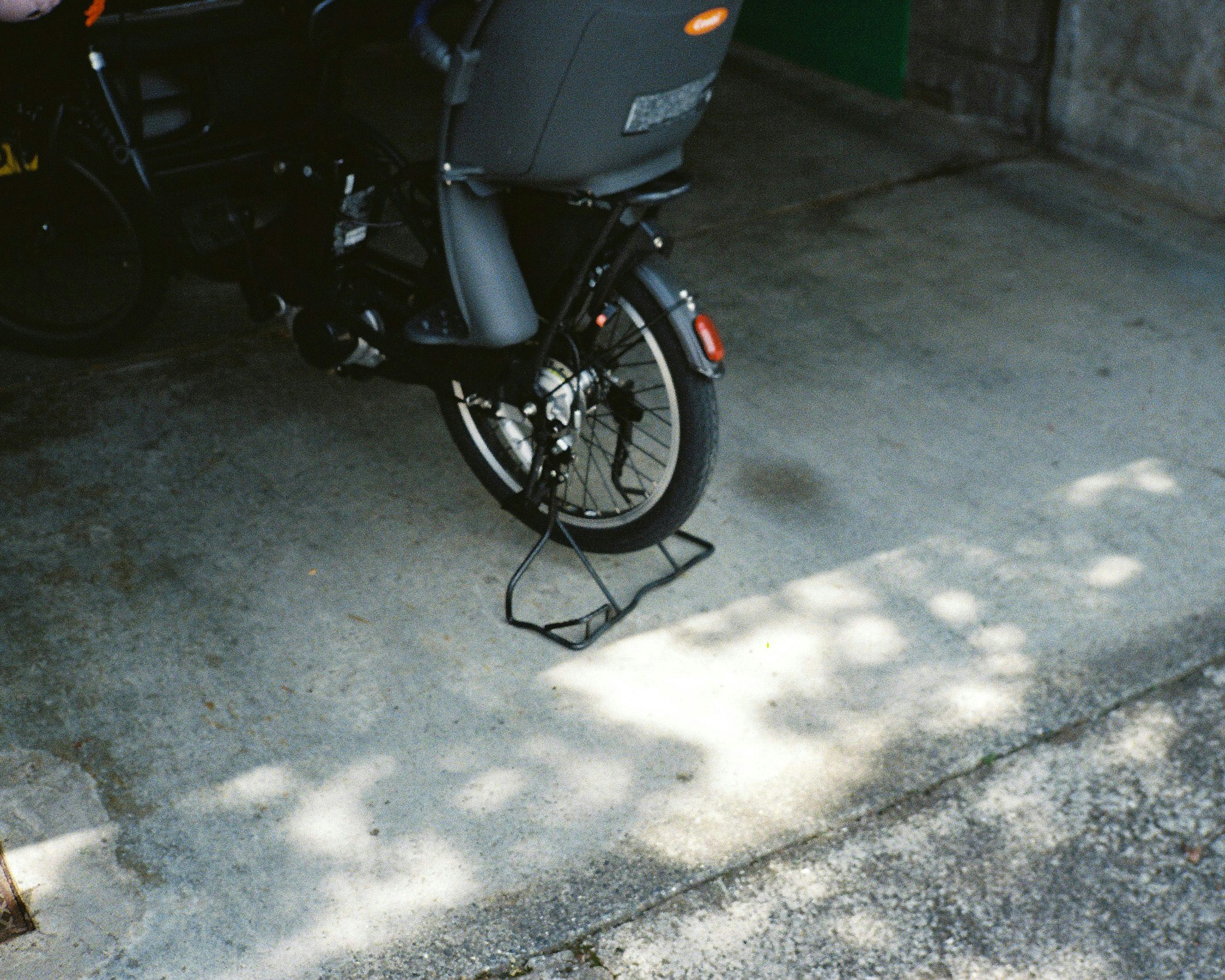 A motorcycle's rear wheel and stand on a concrete surface