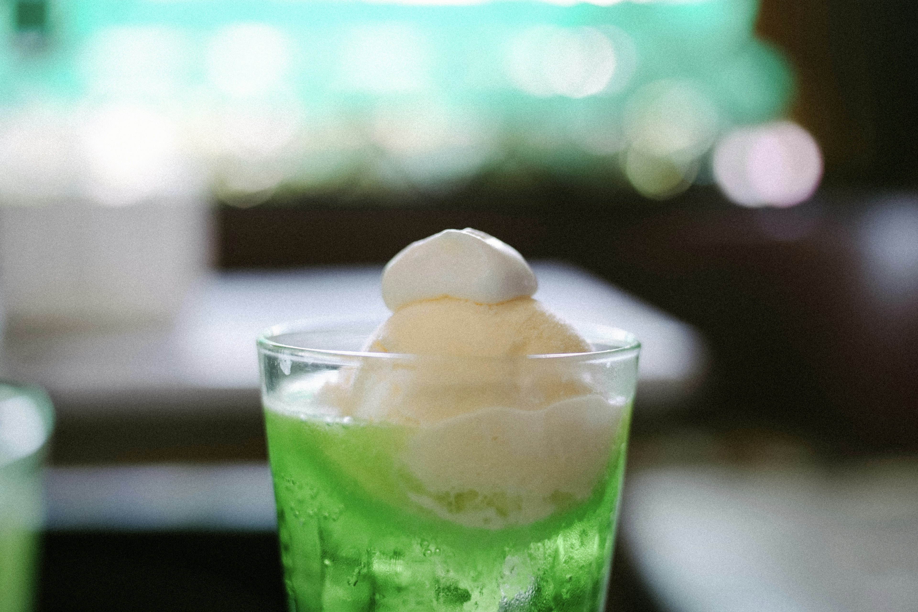 Un verre de soda vert surmonté de crème glacée blanche