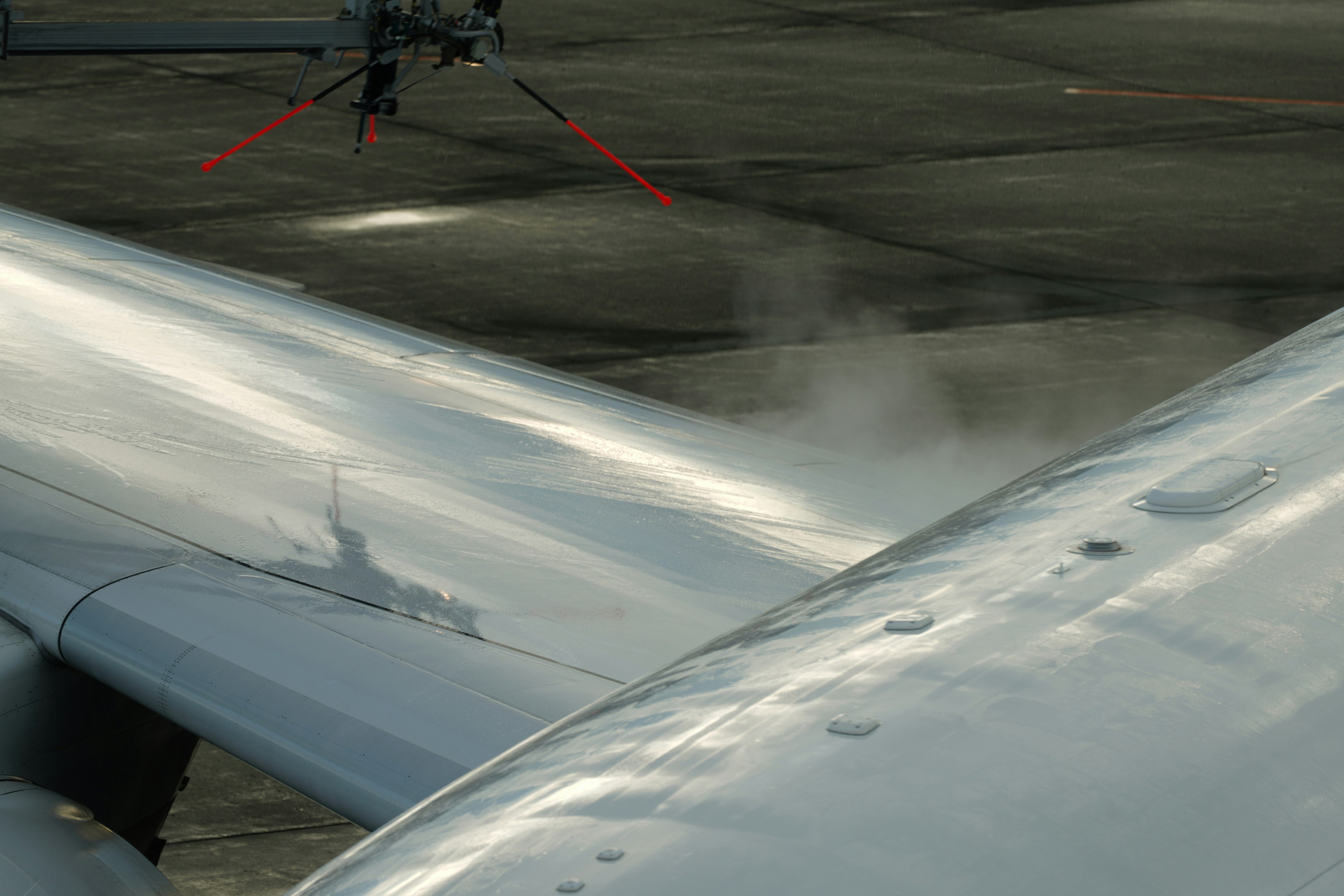 Gros plan sur l'aile d'un avion avec de la brume et un éclat métallique à l'aéroport