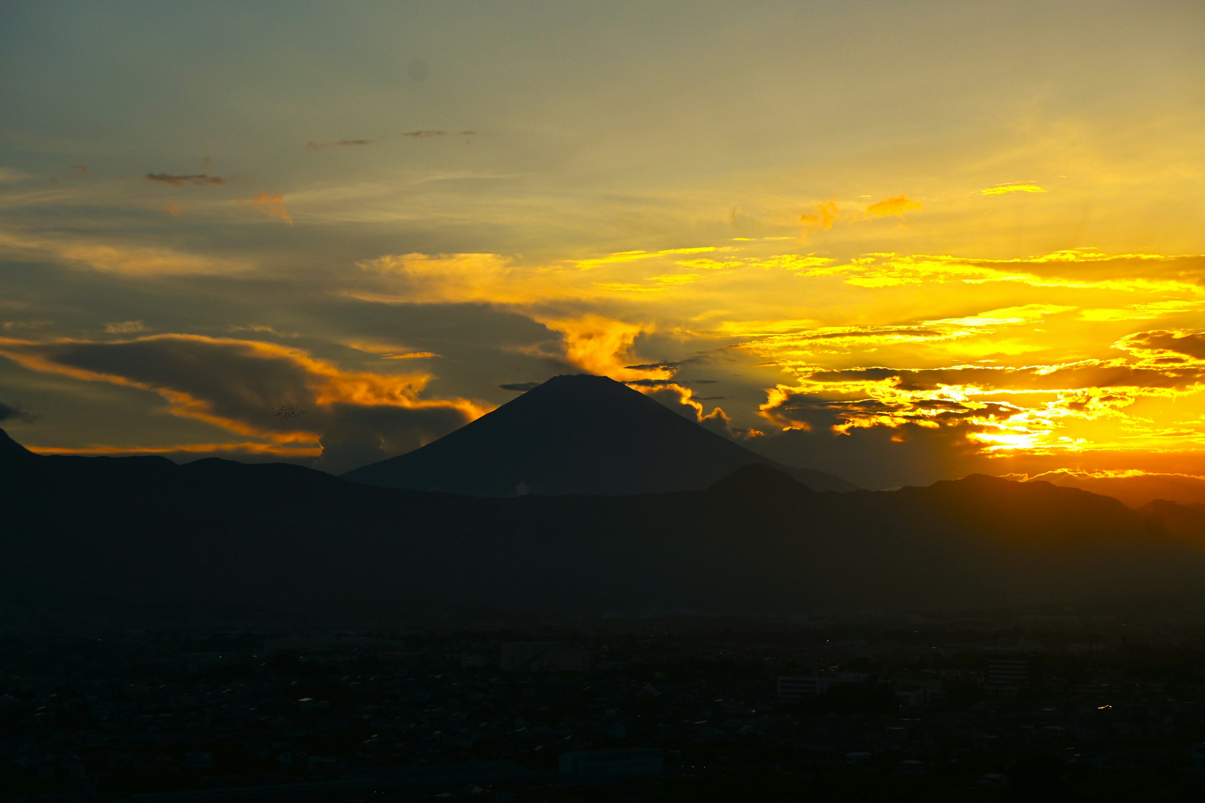 Silhouette di una montagna contro un vivace tramonto con nuvole