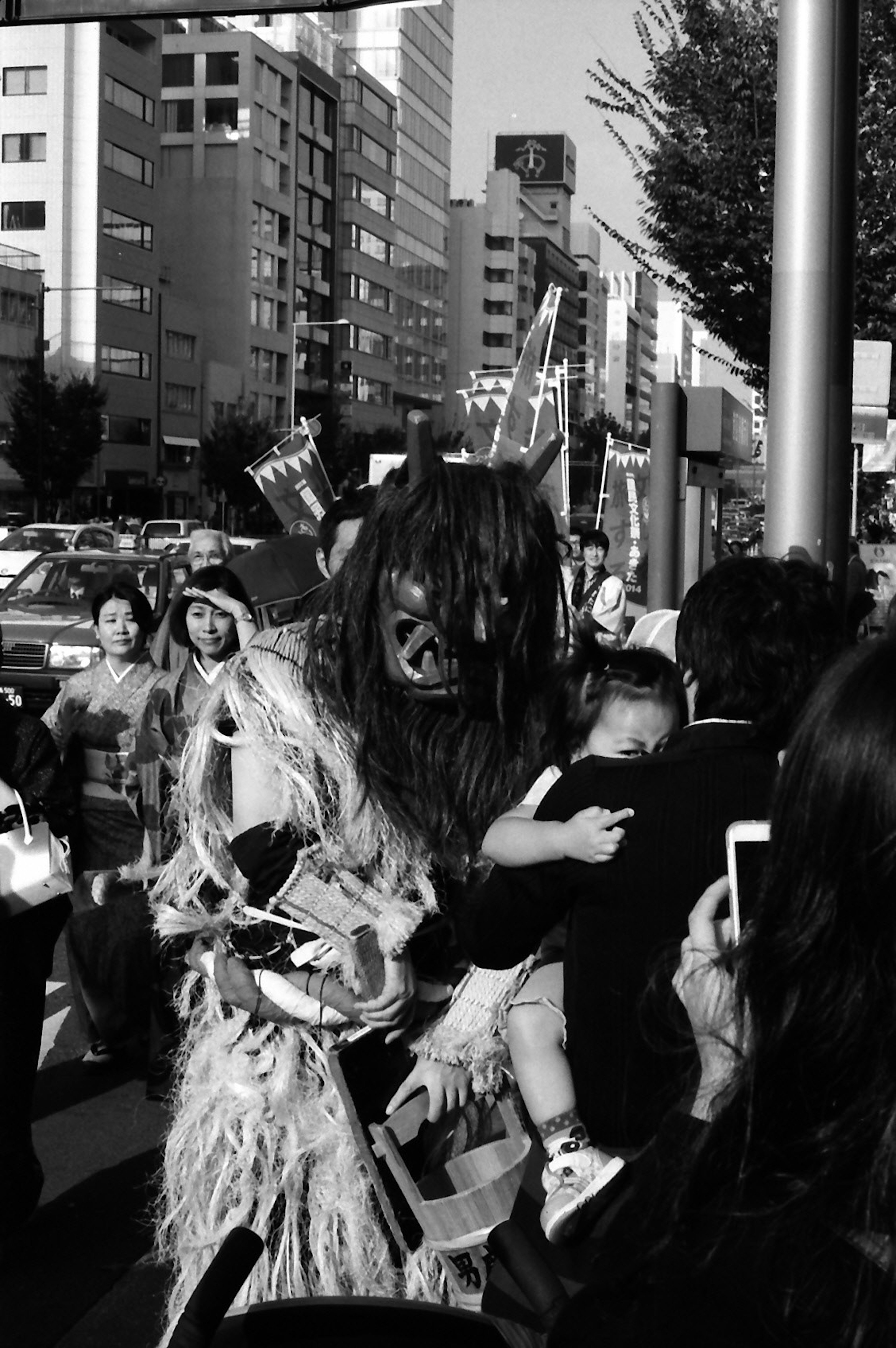 Un personnage costumé tenant un enfant dans une rue animée avec des gens autour