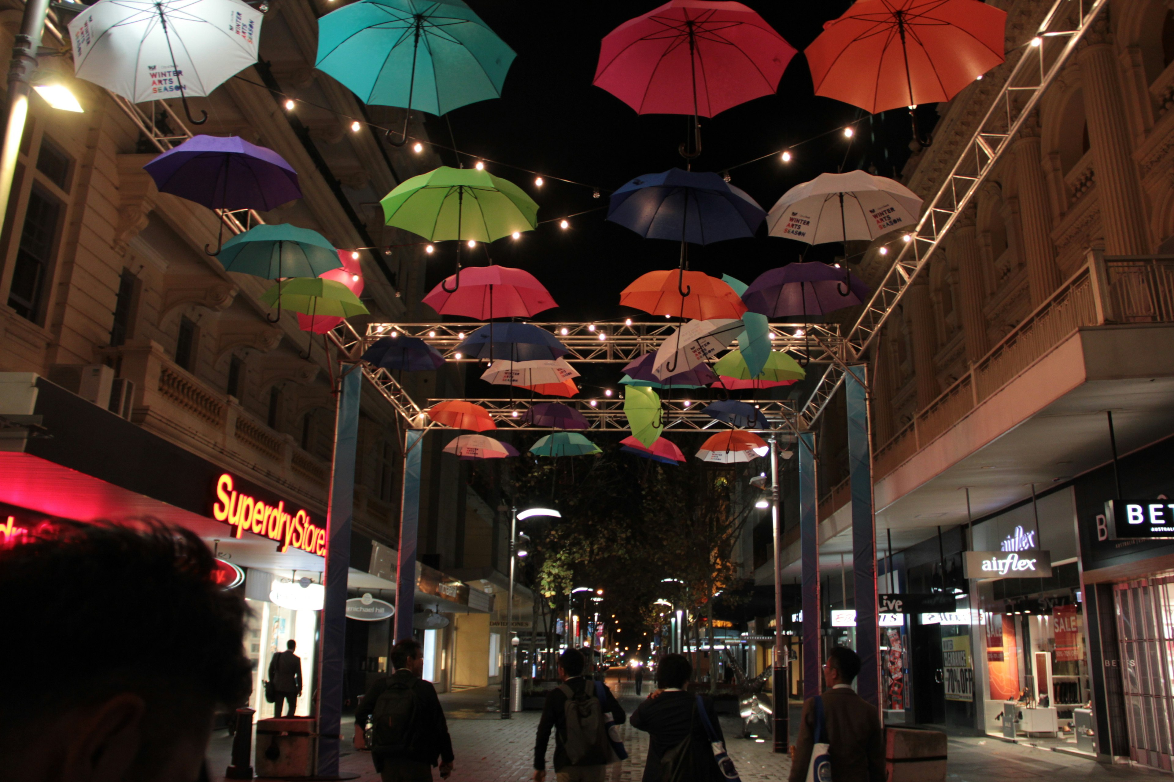 Colorful umbrellas hanging in a street at night with bright lights