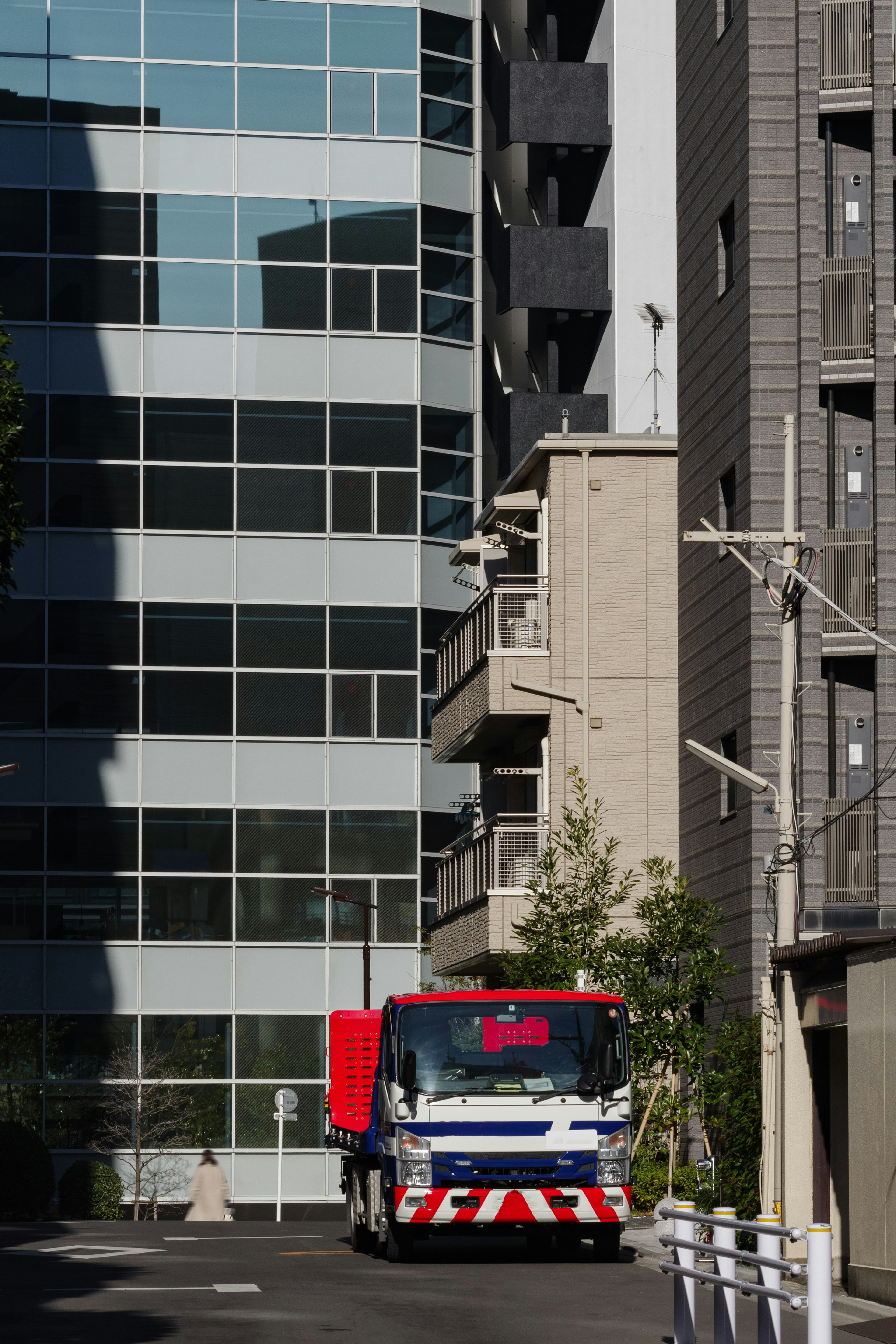 一輛紅藍相間的卡車停在建築物之間