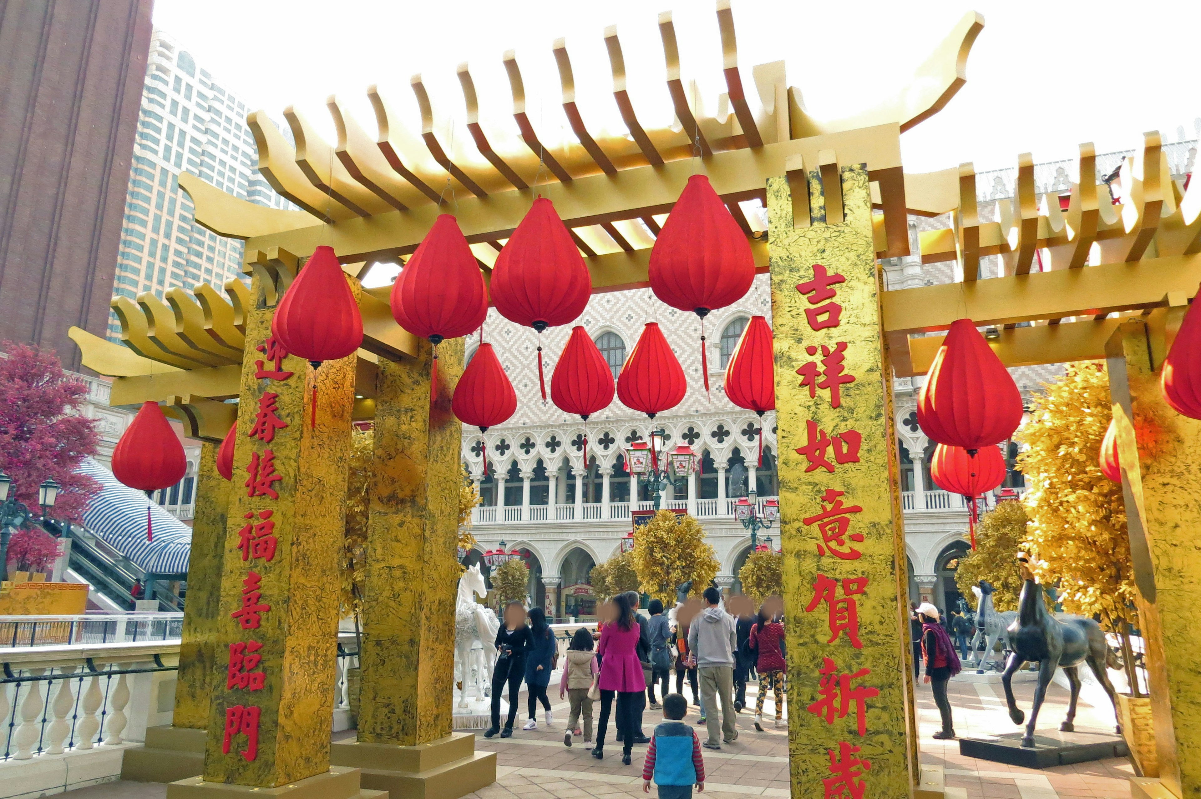 A vibrant entrance featuring a golden arch adorned with red lanterns with people gathered around