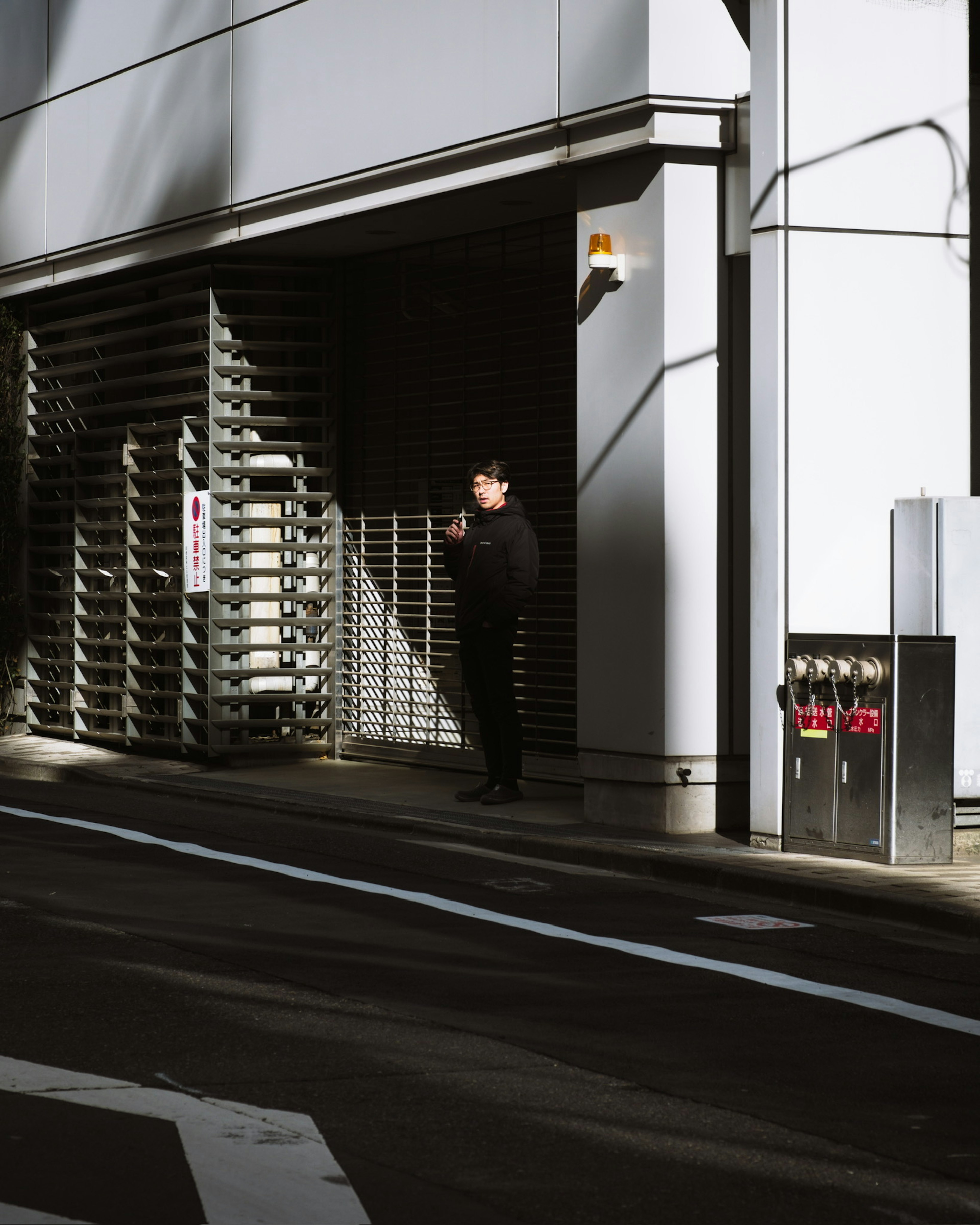 街の一角に立つ人物とシャッターがある風景