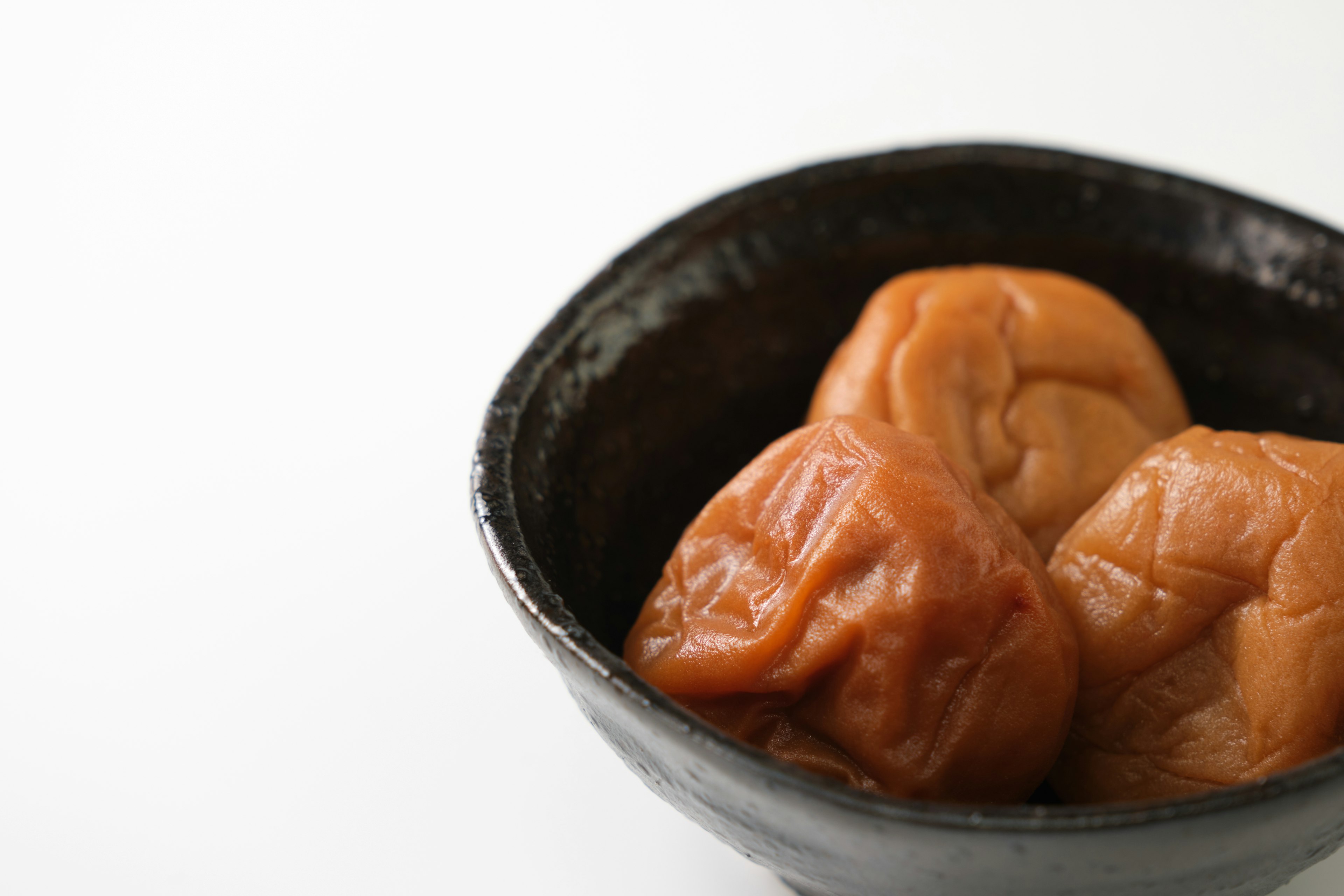 Trois morceaux d'umeboshi dans un bol noir