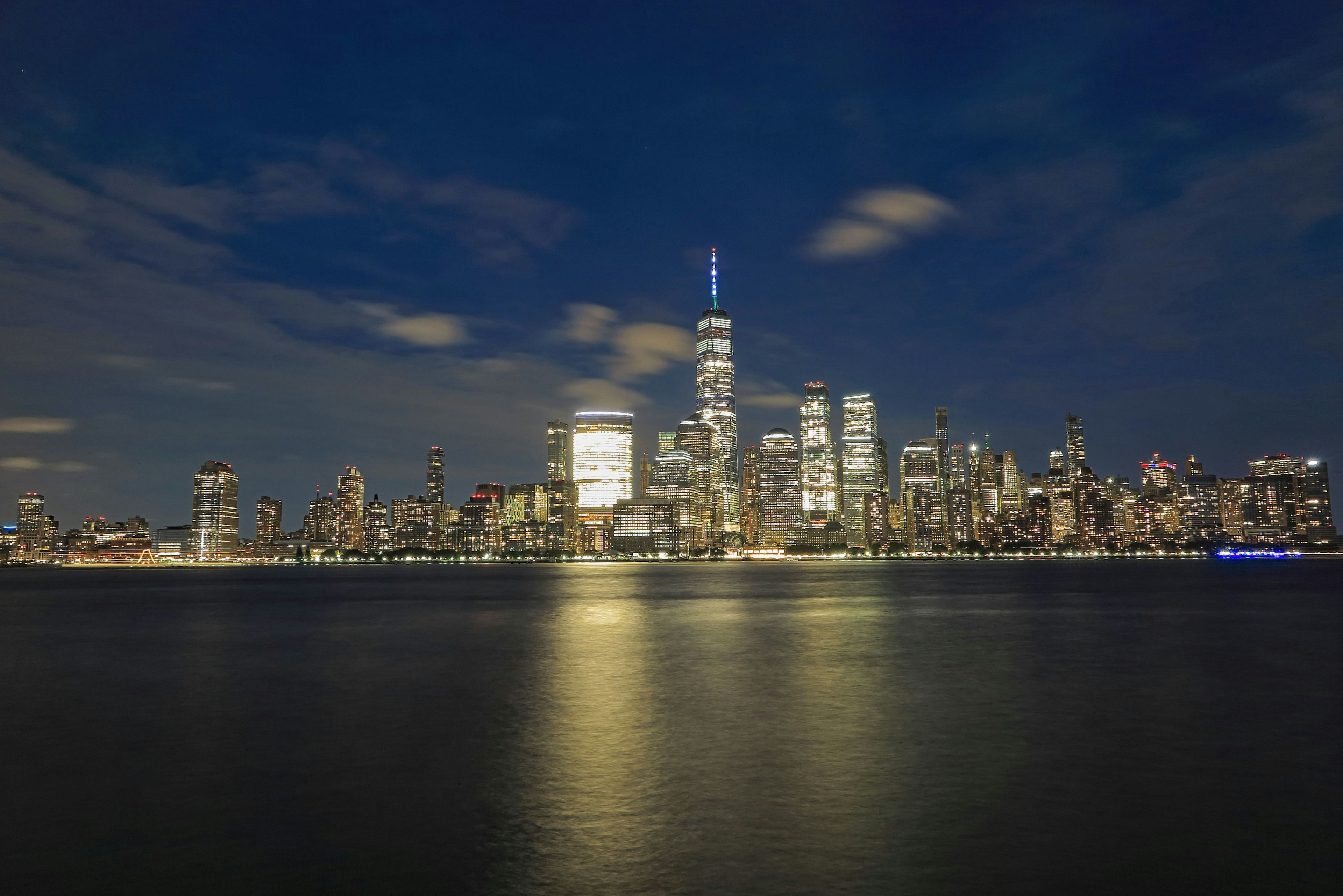 Garis langit New York di malam hari gedung pencakar langit yang diterangi memantul di air