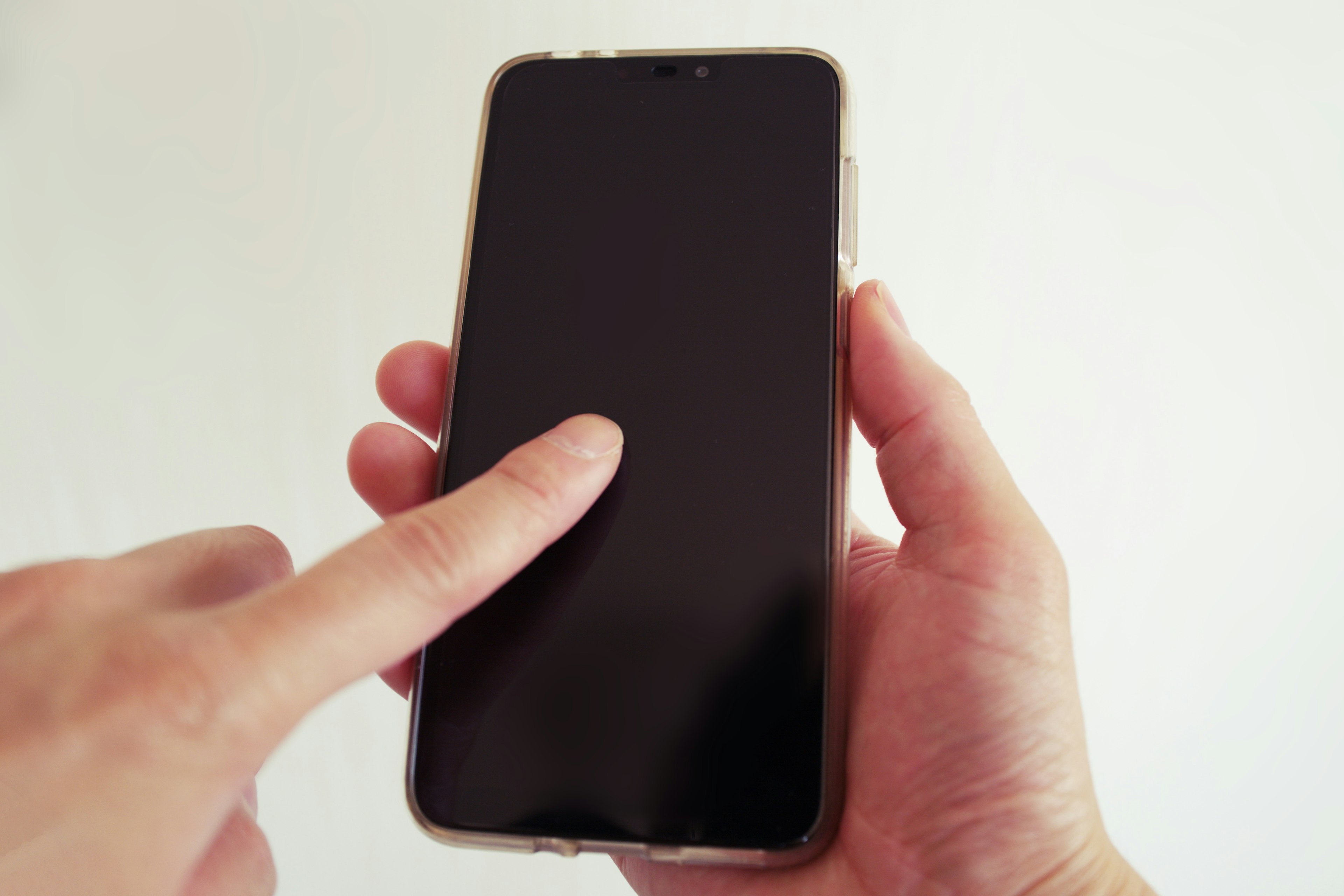 A finger touching a smartphone held in a hand