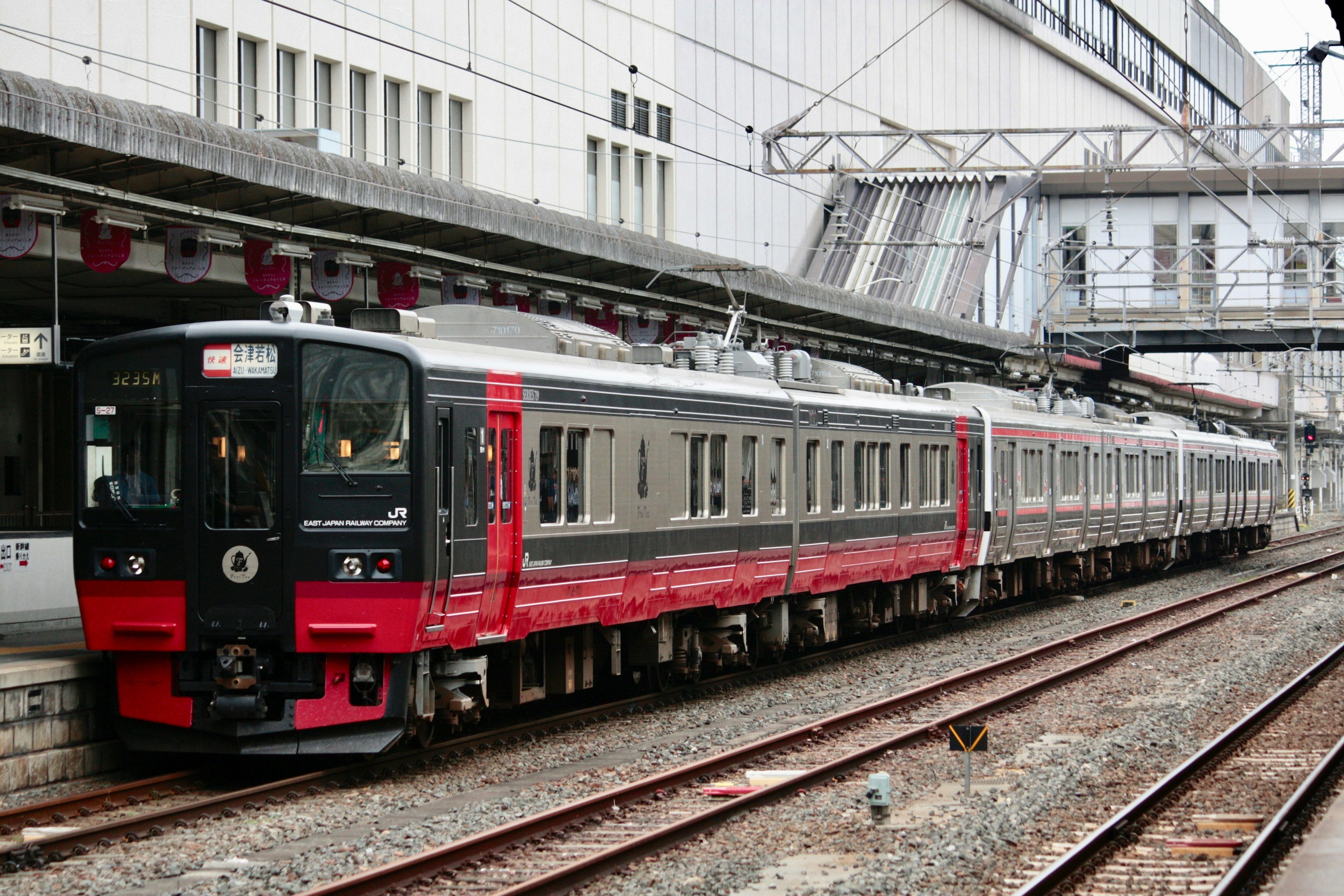 Kereta dengan desain merah dan perak diparkir di stasiun