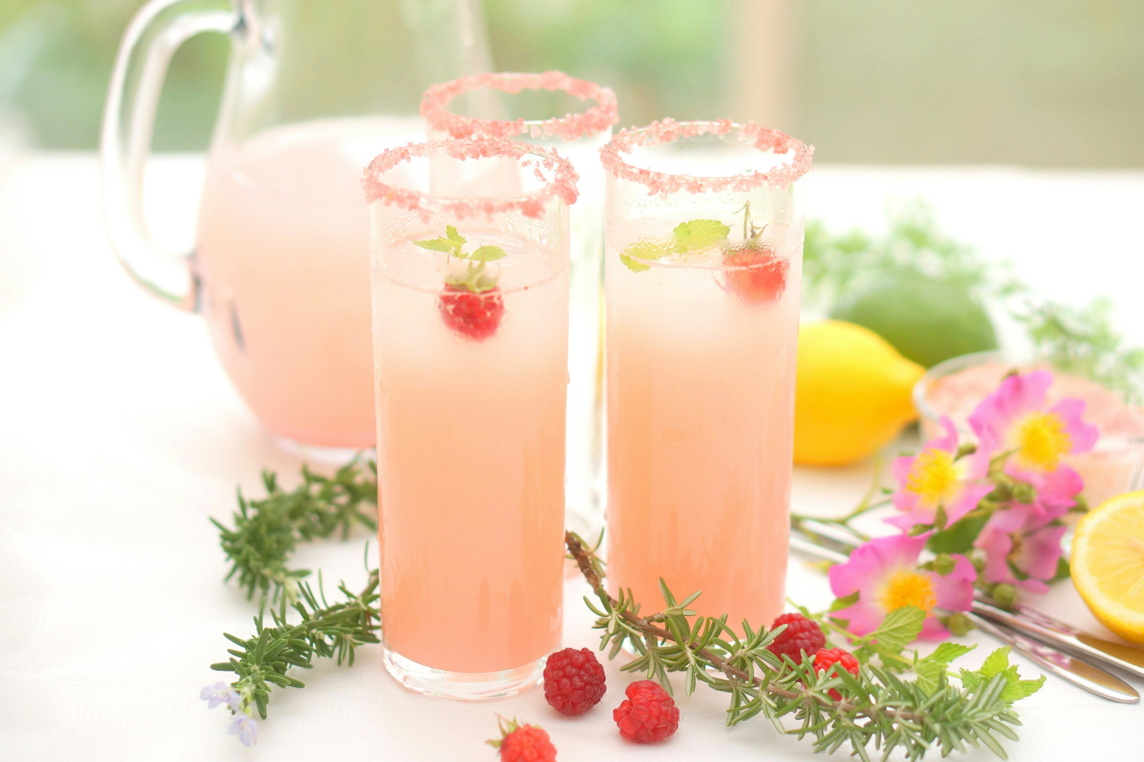 Pink cocktail glasses garnished with raspberries and mint