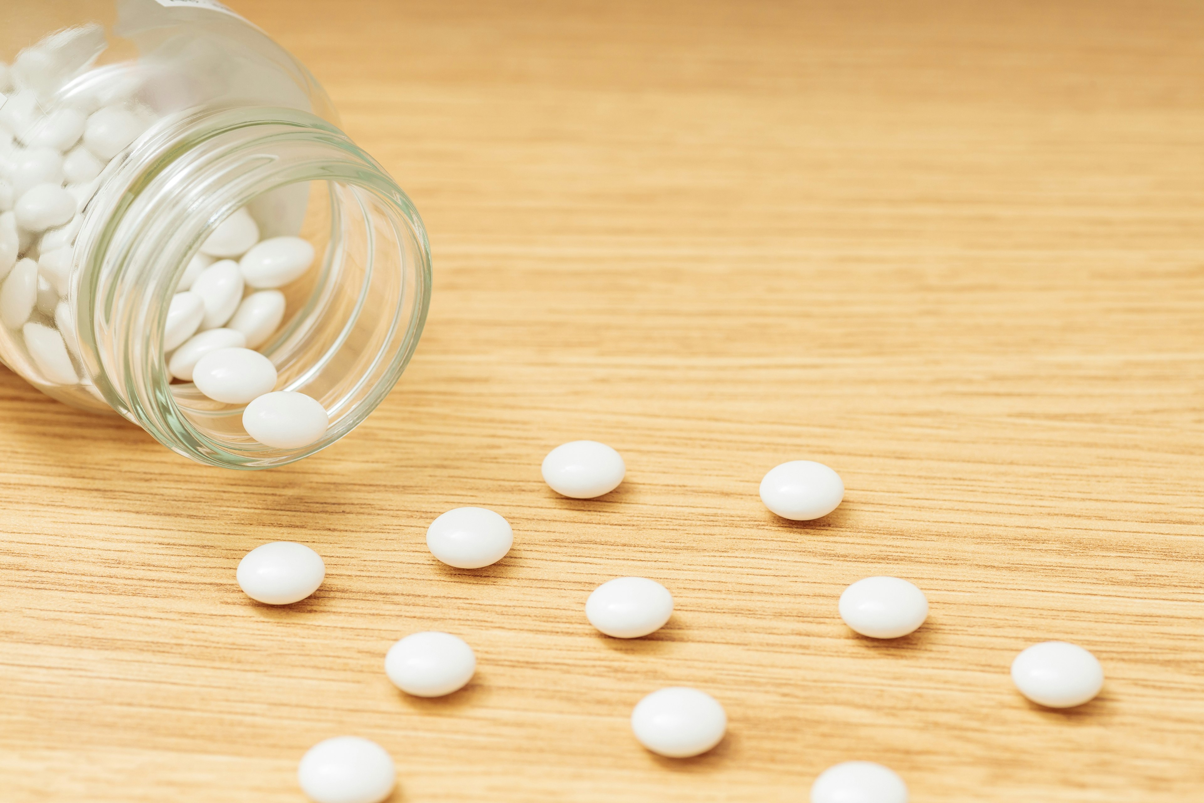 White pills scattered on a wooden table