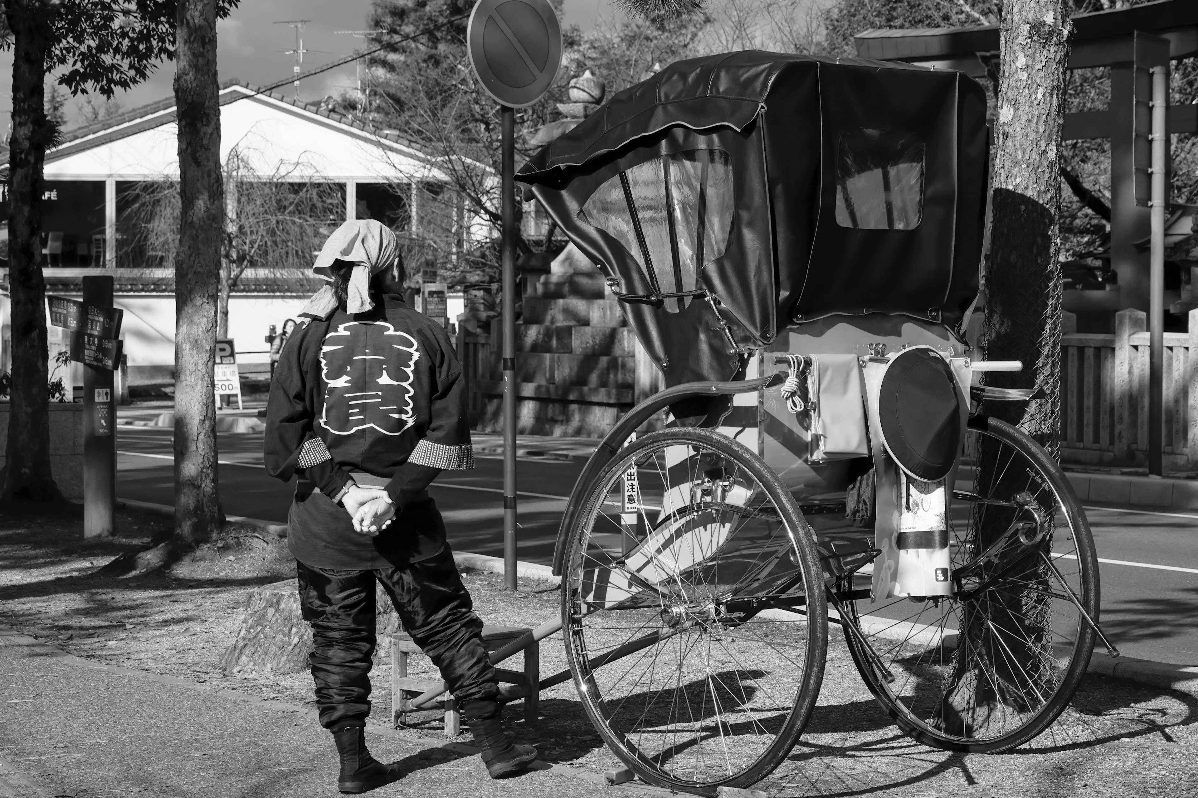 Una persona con atuendo tradicional de pie junto a un rickshaw