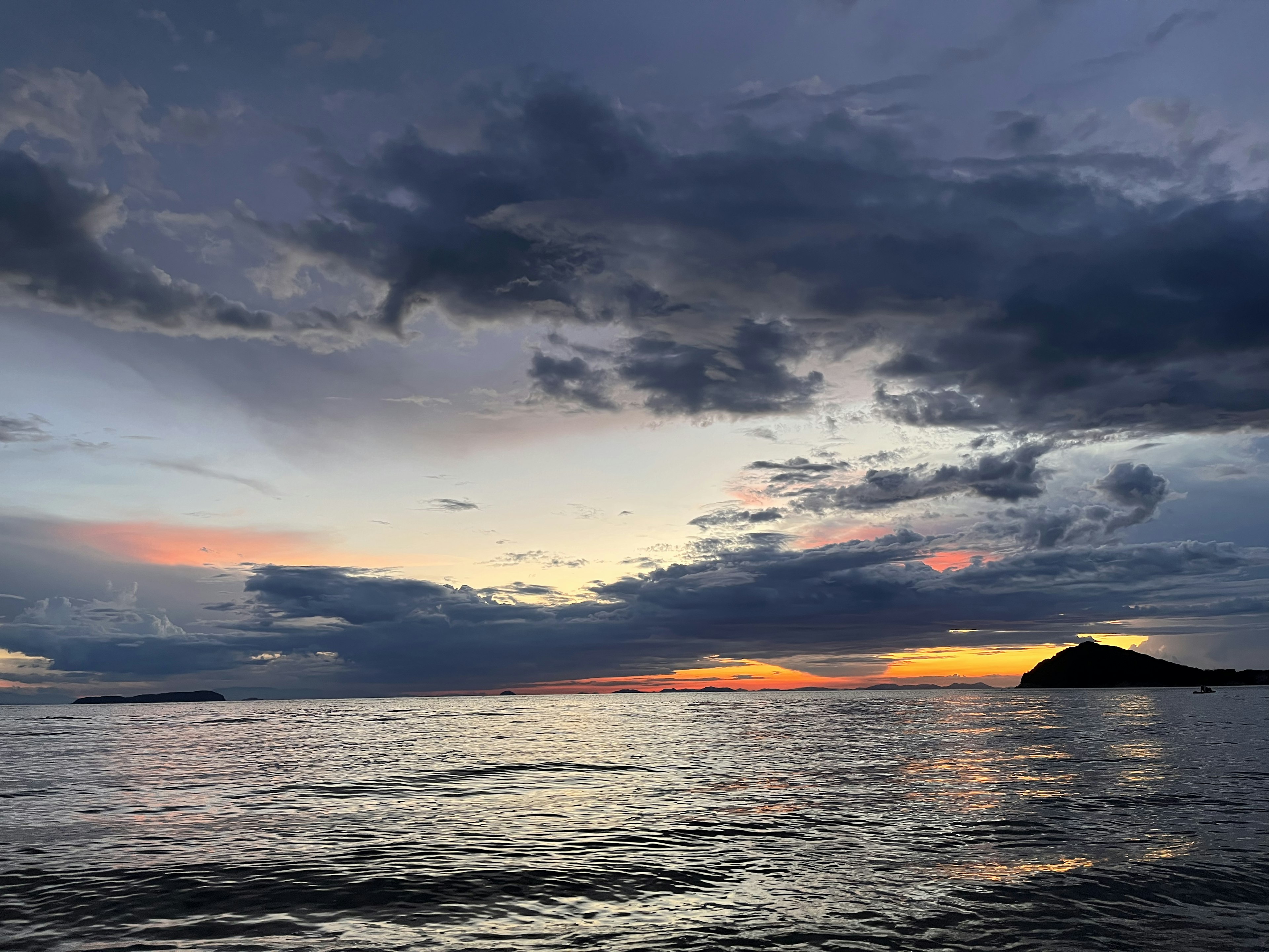 静かな海と壮大な夕焼けの景色 雲が広がる空と遠くの島