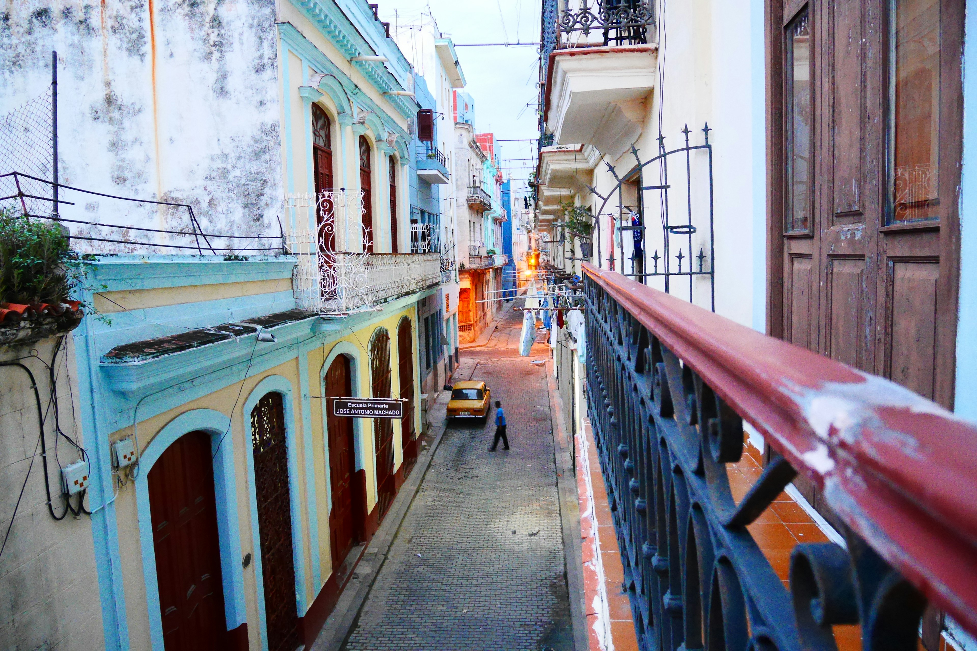 Escena de calle estrecha con edificios coloridos y una persona caminando