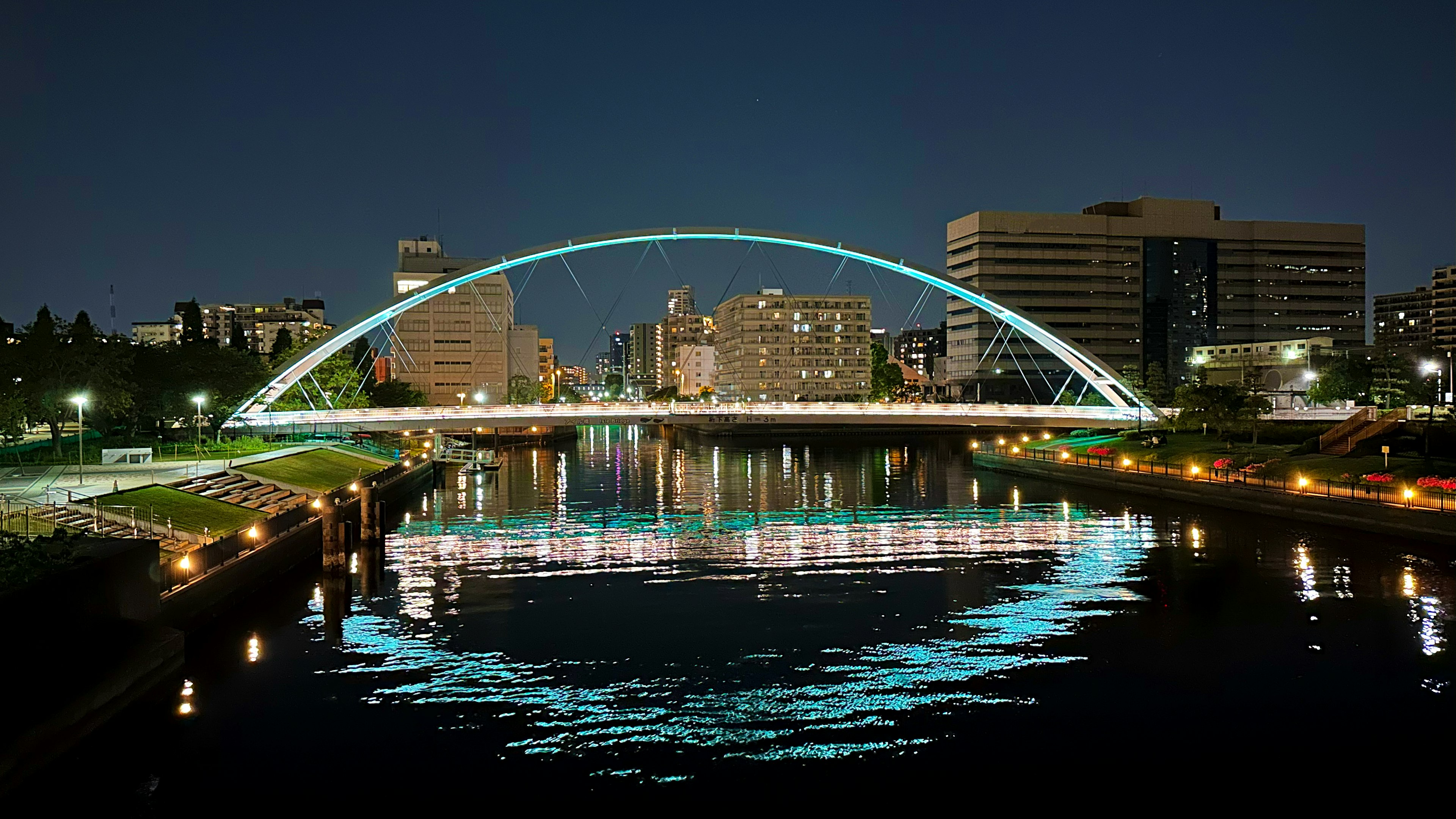 Arched bridge illuminated at night with reflections in the water